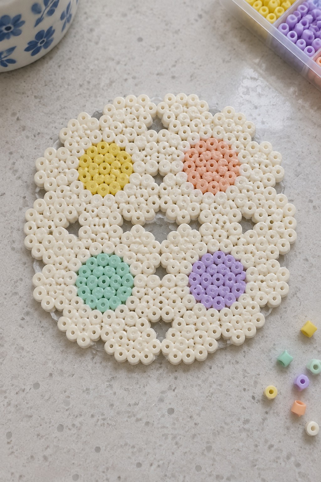 Circular perler bead flower with yellow, peach, mint, and purple centers