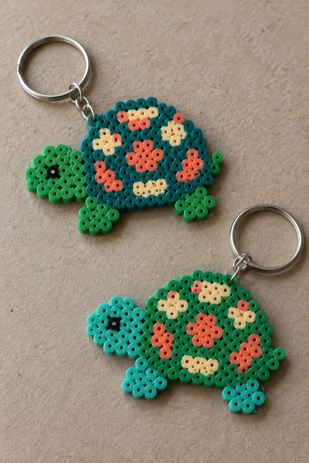Two perler bead turtle keychains with green shells, patterned backs, and metal rings.