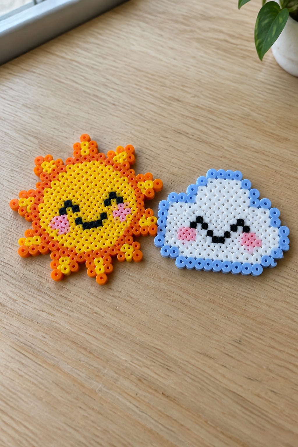 Perler bead sun and cloud with smiling faces on wooden table