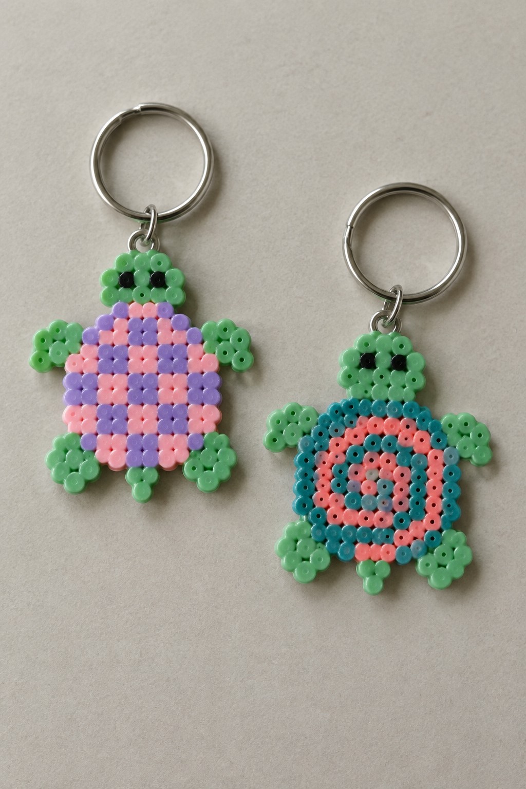Two perler bead turtle keychains with pink-purple and blue-pink shells on silver rings.