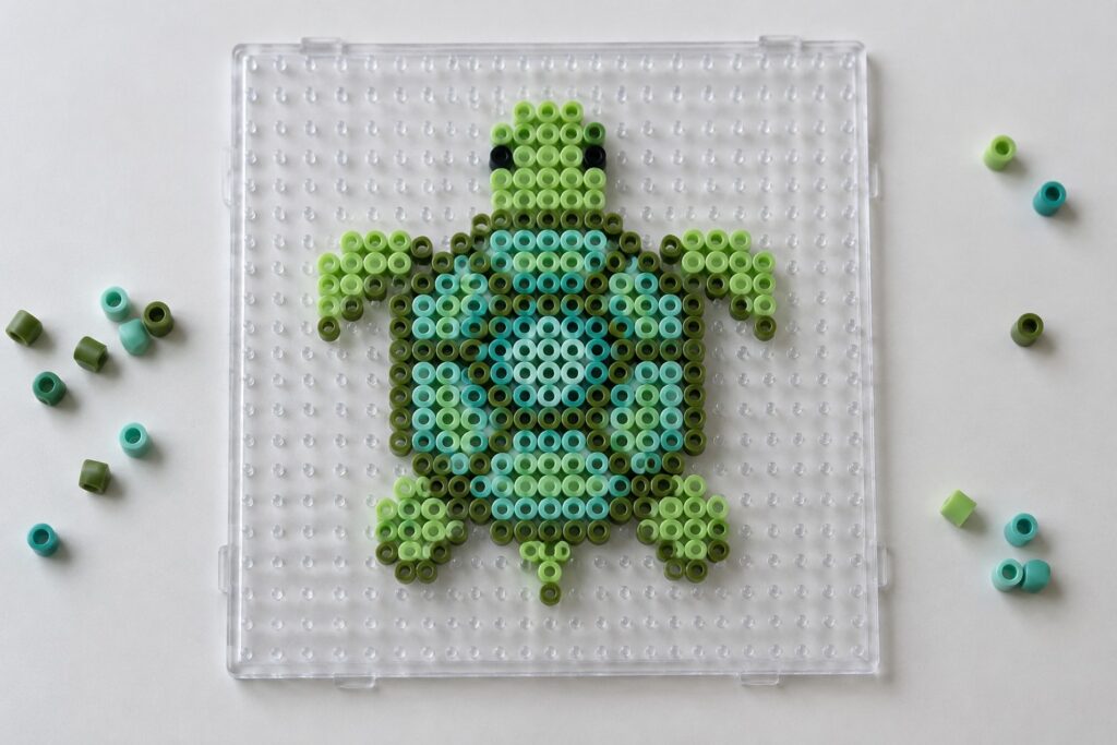 16 Turtle Perler Bead Designs Featuring Detailed Shell Patterns Green Perler bead turtle on clear pegboard with scattered loose beads around