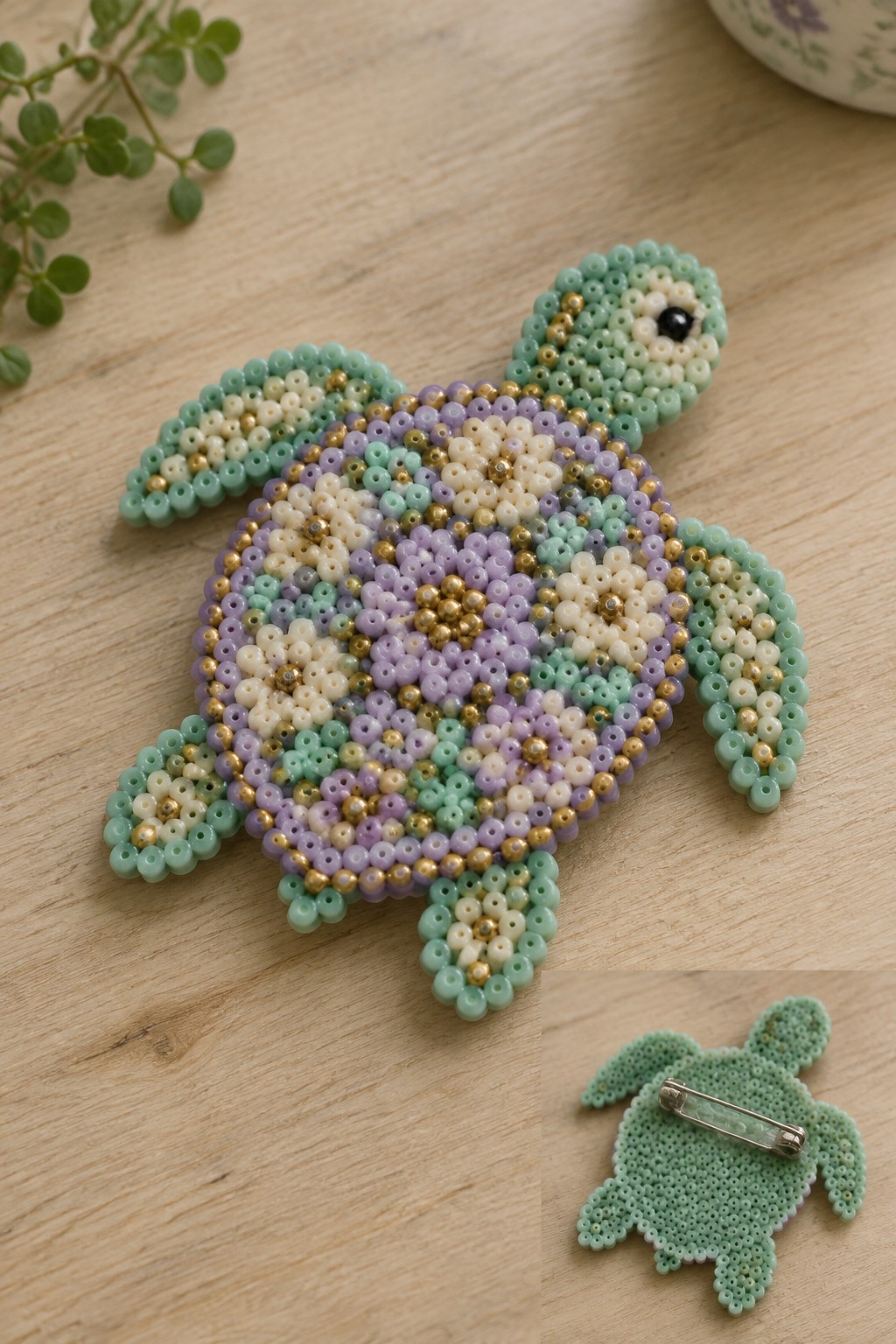 Perler bead turtle with purple, mint green, white, and gold patterned shell on a pegboard, with an inset of the fused back showing a safety pin.