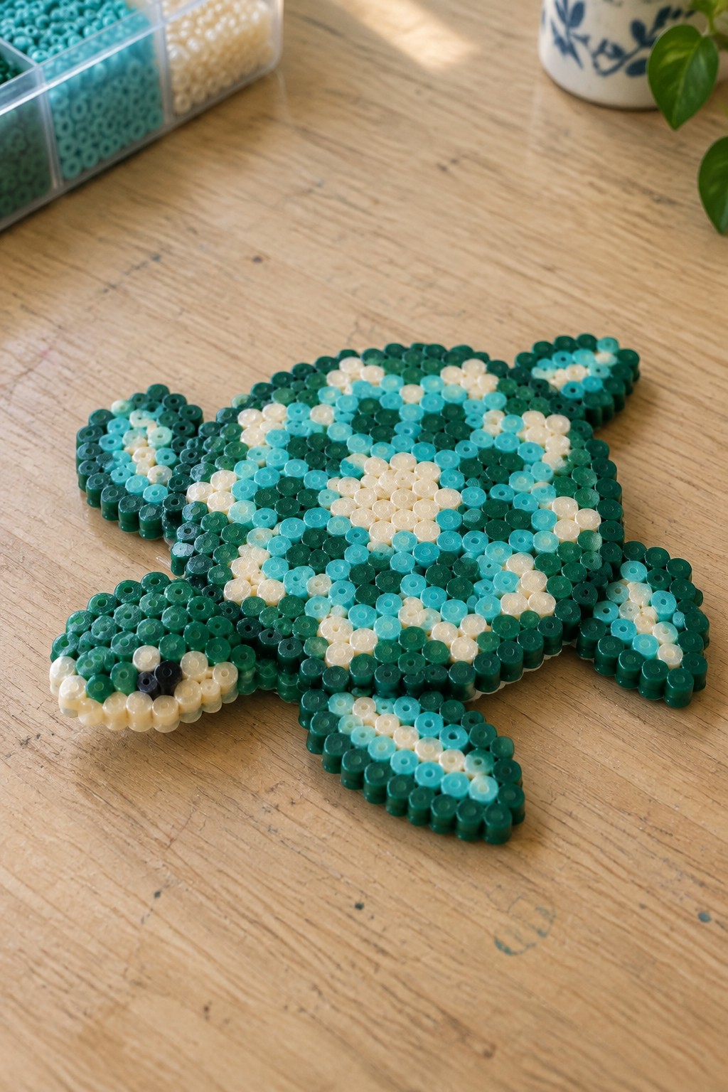 Vibrant perler bead sea turtle in green blue and white on wooden table