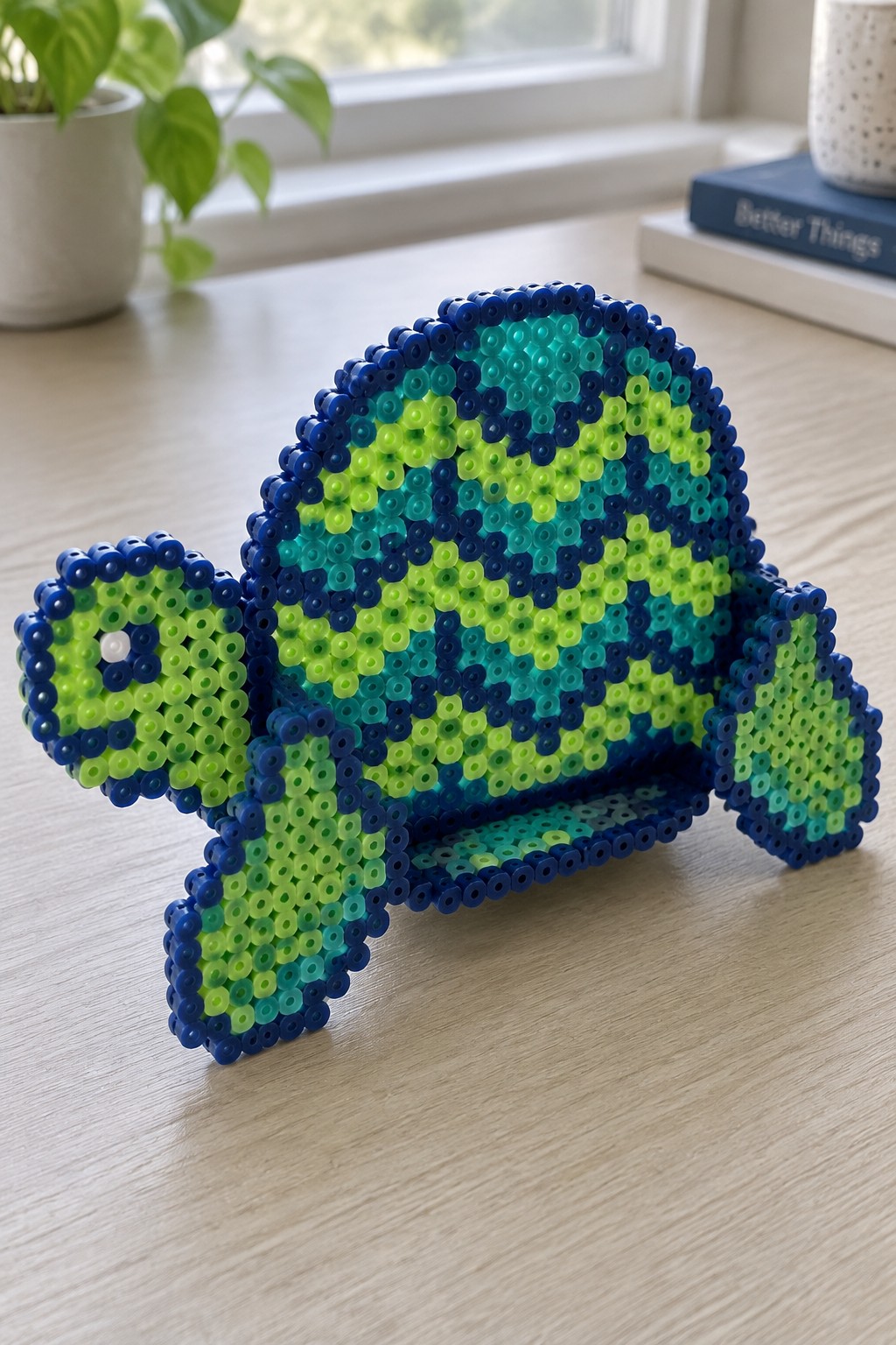 Blue and green perler bead turtle figurine on wooden table