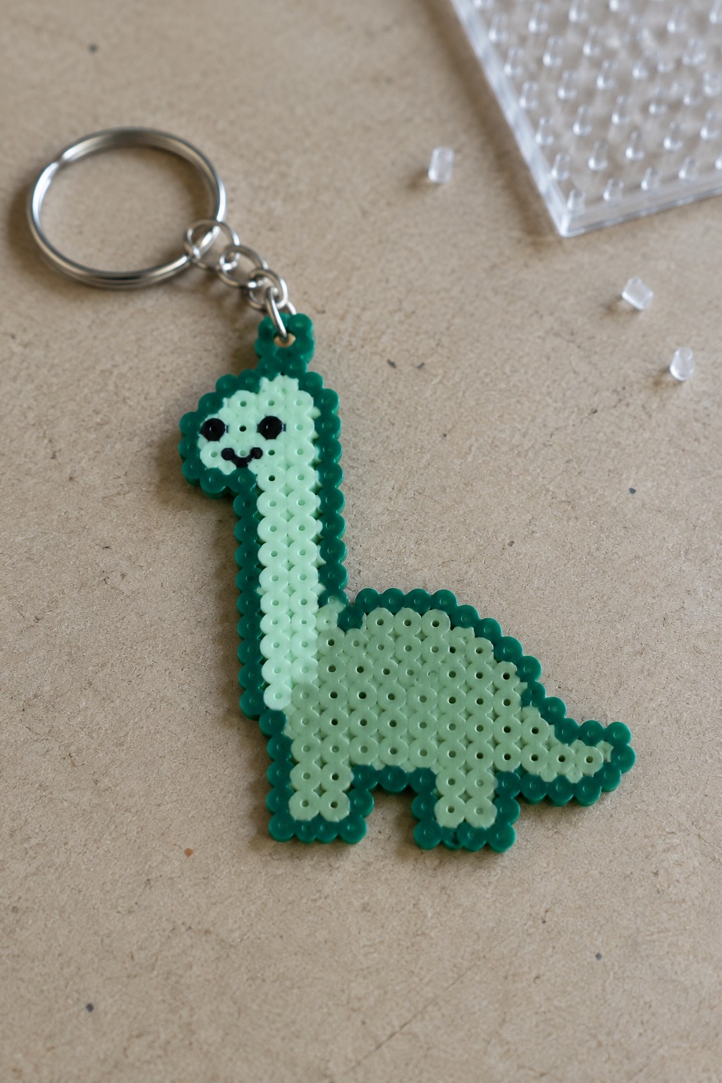 Green perler bead long-necked dinosaur keychain with smiling face on silver ring