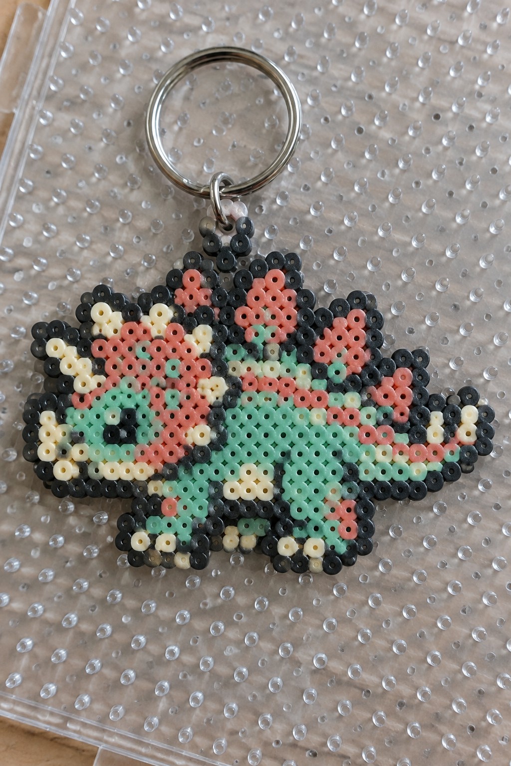 Perler bead keychain with pink, mint green, and black pixel art on metal ring