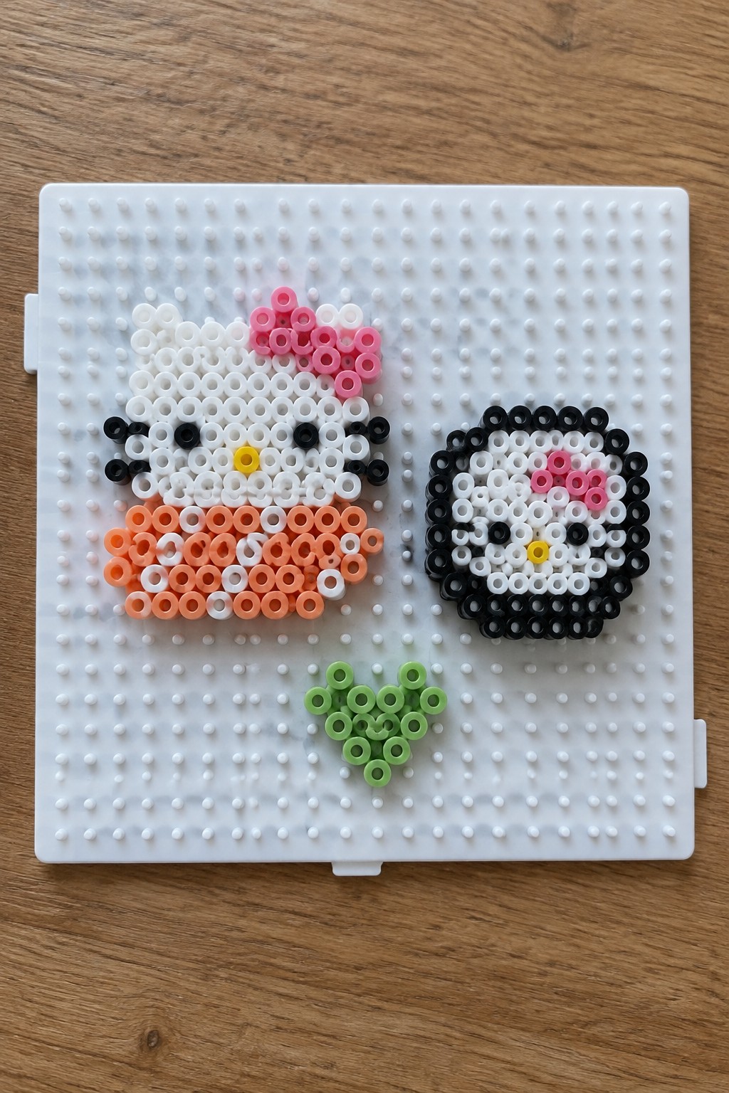 Hello Kitty and sushi Hello Kitty perler beads with green heart on pegboard