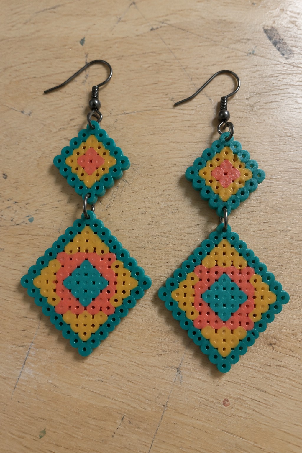 Pair of colorful Perler bead dangle earrings in teal, yellow, and pink.