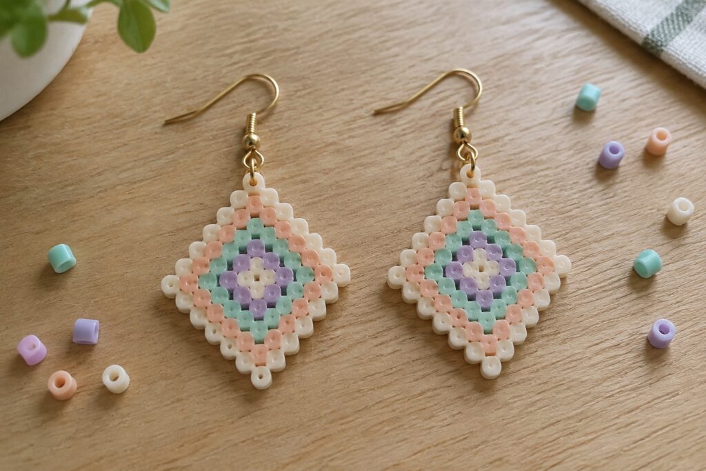 Pair of pastel beaded diamond earrings in peach, mint, purple on wood table
