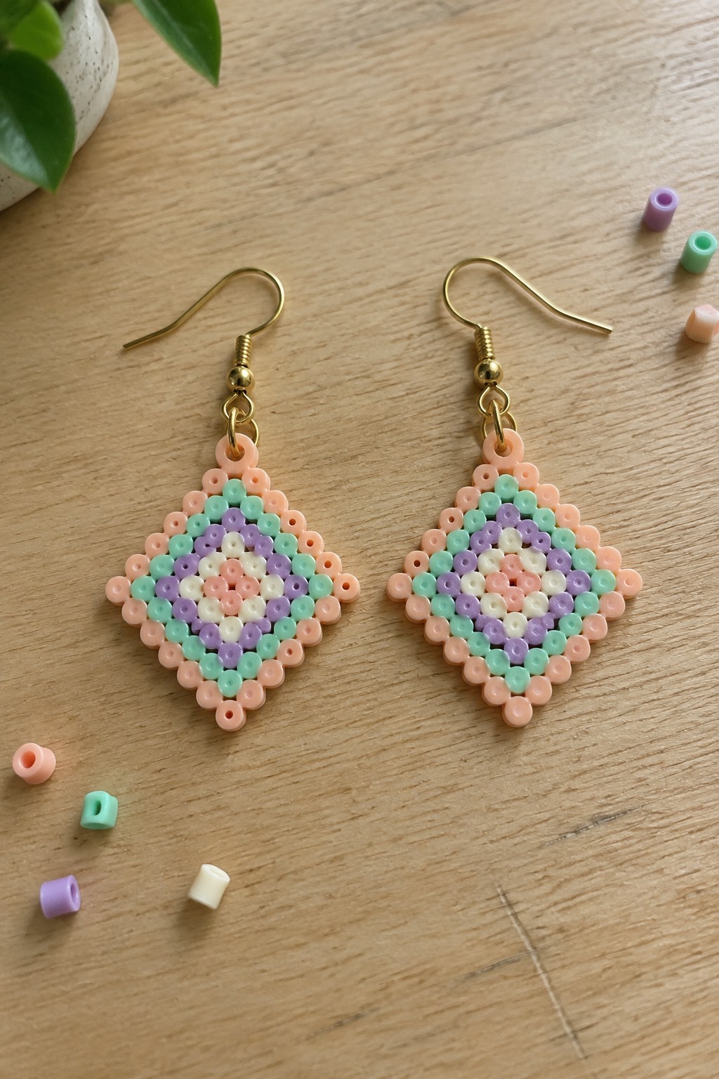Pair of pastel beaded diamond earrings in peach, mint, purple on wood table