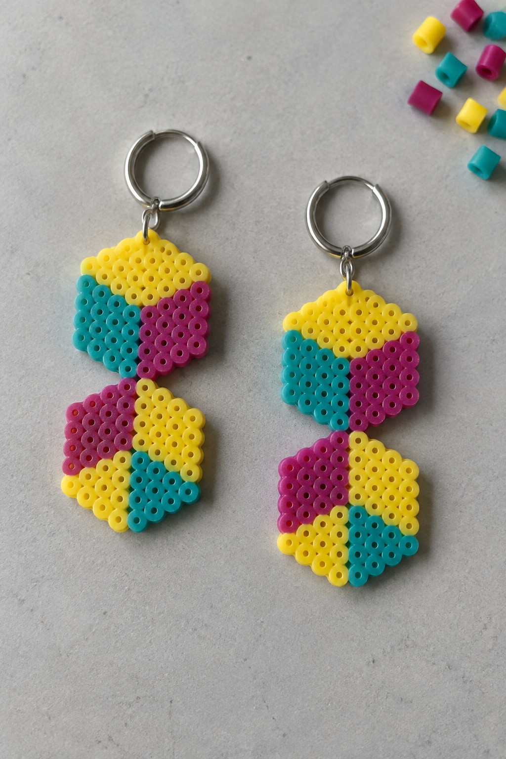 Two colorful perler bead keychains in yellow, cyan, and magenta with silver rings.