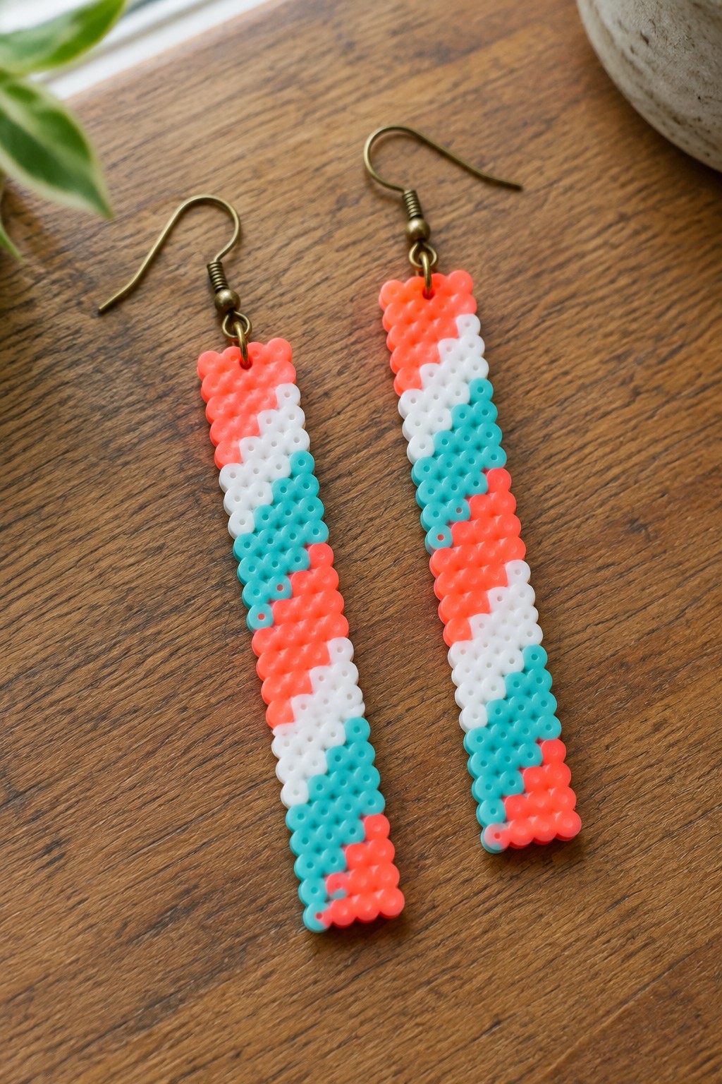Pair of long perler bead earrings in coral, white, and turquoise on wood