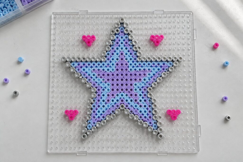 17 Y2K Perler Bead Designs Featuring Retro Stars and Hearts Star-shaped Perler bead pattern in blue, purple, and silver on clear pegboard with pink accents