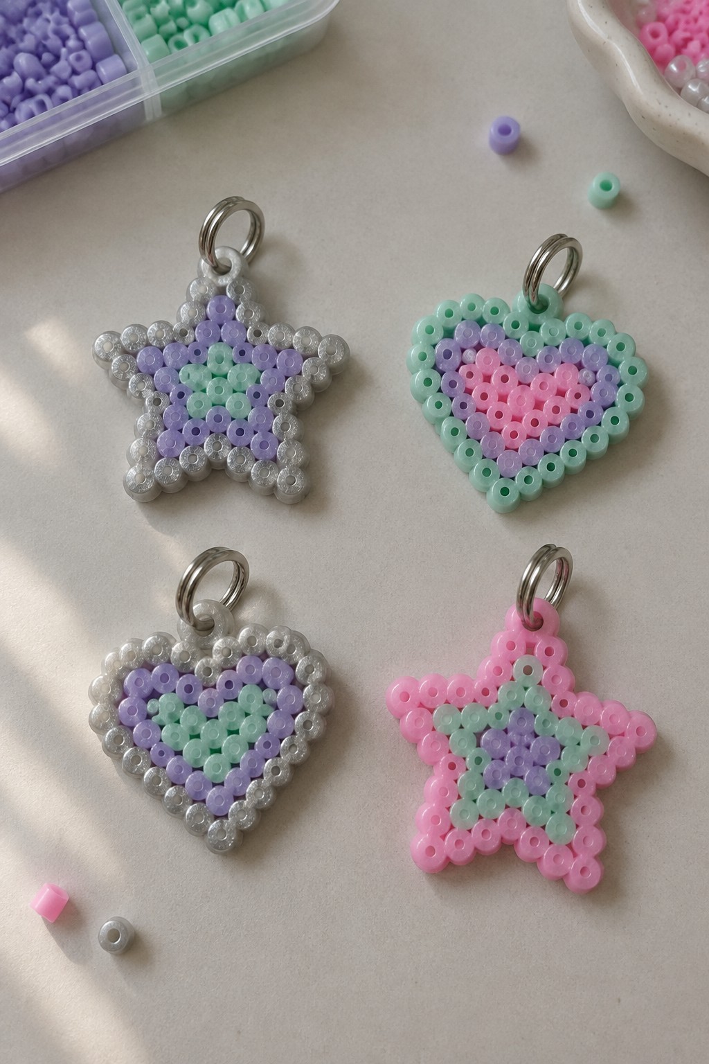 Four pastel perler bead stars and hearts with silver borders and keyrings