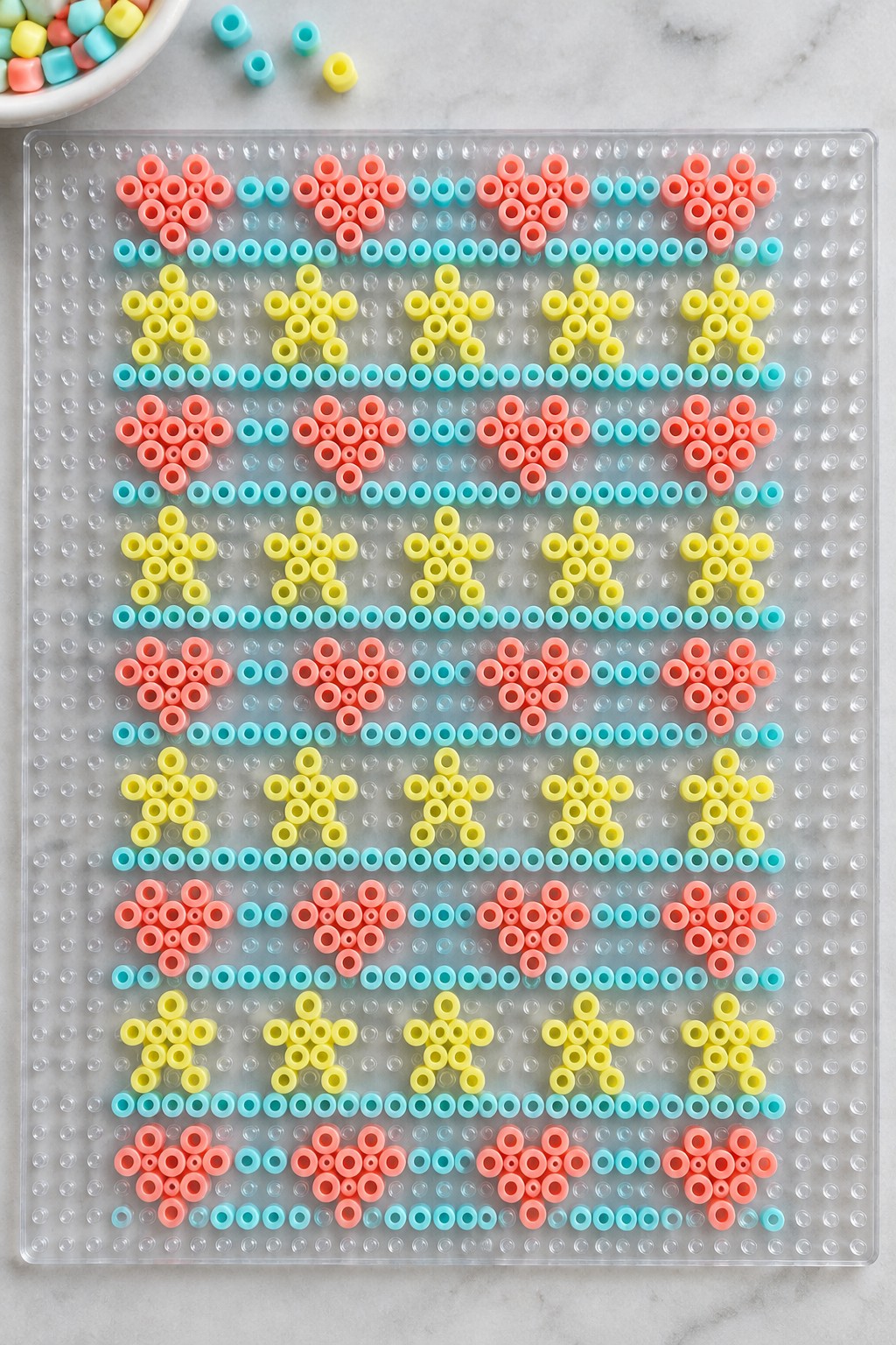 Pink flower and yellow star bead patterns on a clear pegboard
