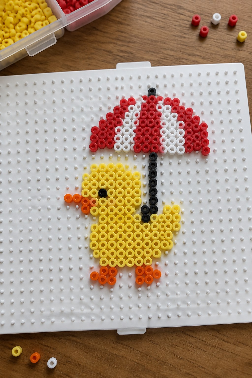Yellow perler bead chick holding red and white umbrella on pegboard