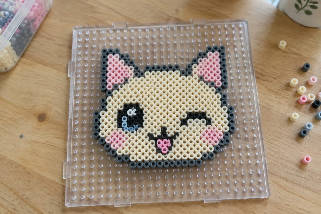 18 Cat Perler Bead Patterns With Playful Expressions Cat face pixel art made with perler beads on clear pegboard
