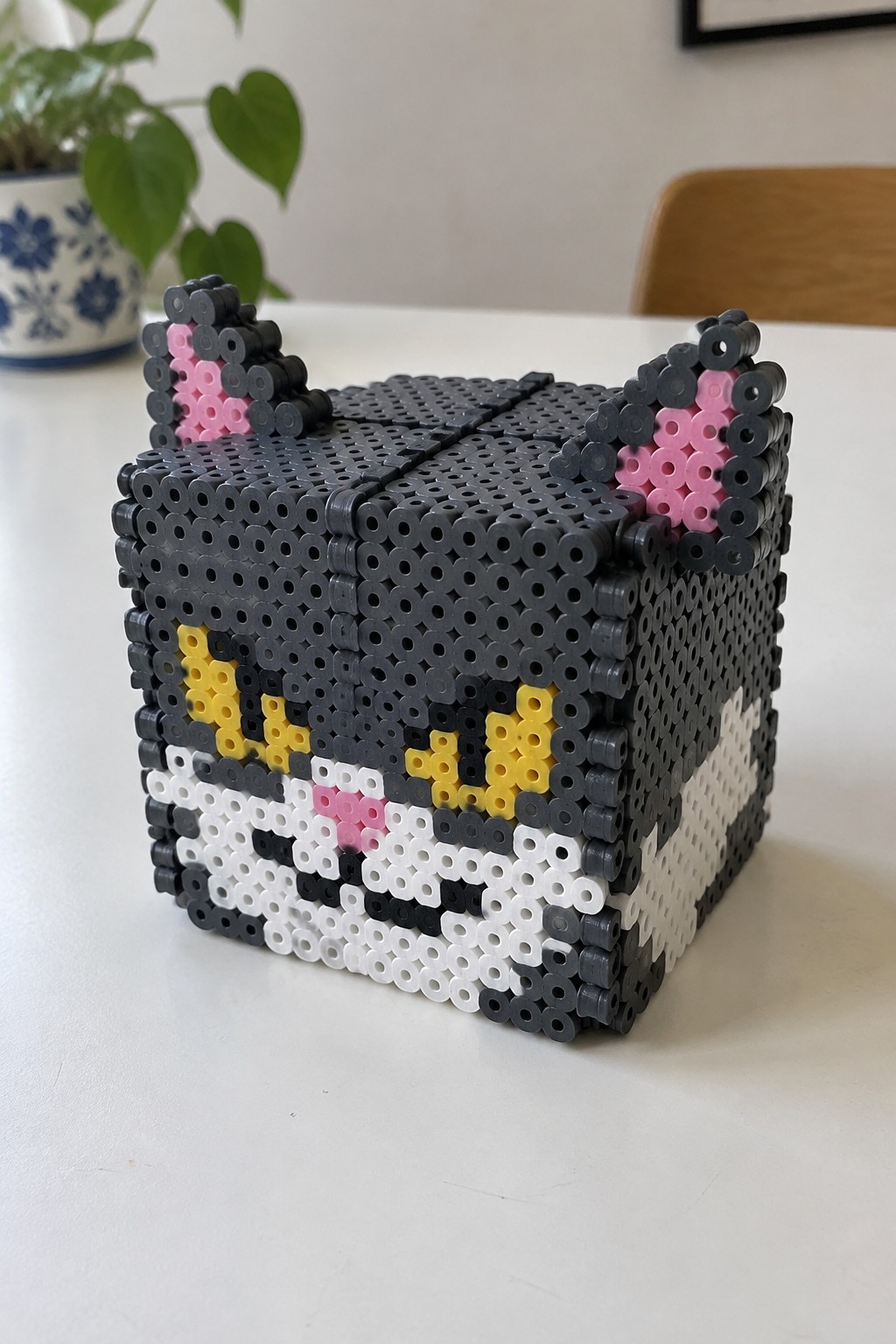 Gray perler bead cube with cat ears, yellow eyes, pink nose and white muzzle