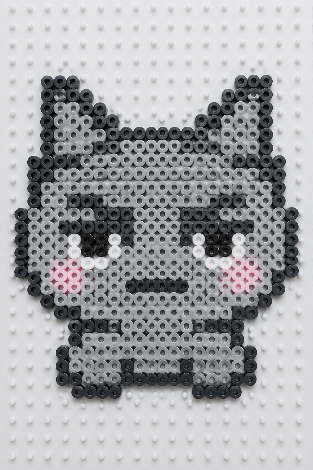 Black and gray perler bead cat with pink cheeks on pegboard