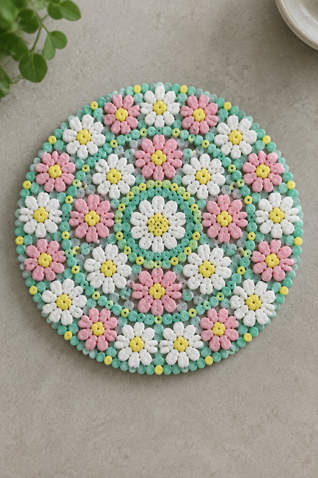 Pastel beaded coaster with layered flower designs in pink, yellow, and green.