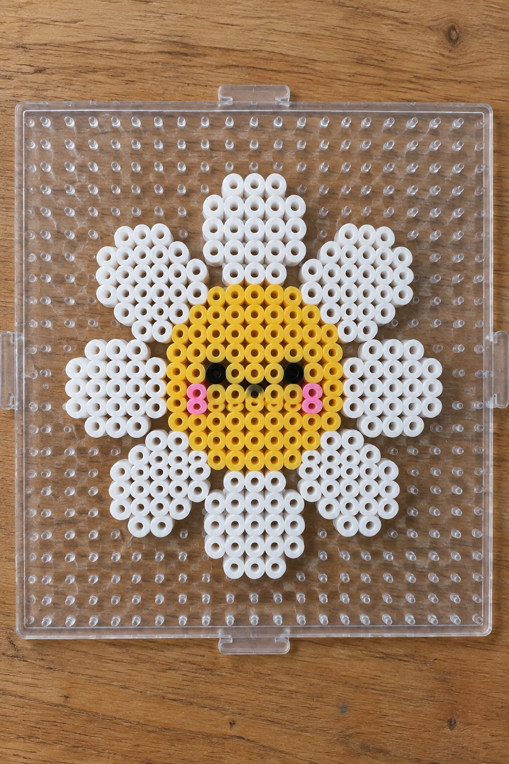 Perler bead daisy with yellow face center and white petals on pegboard