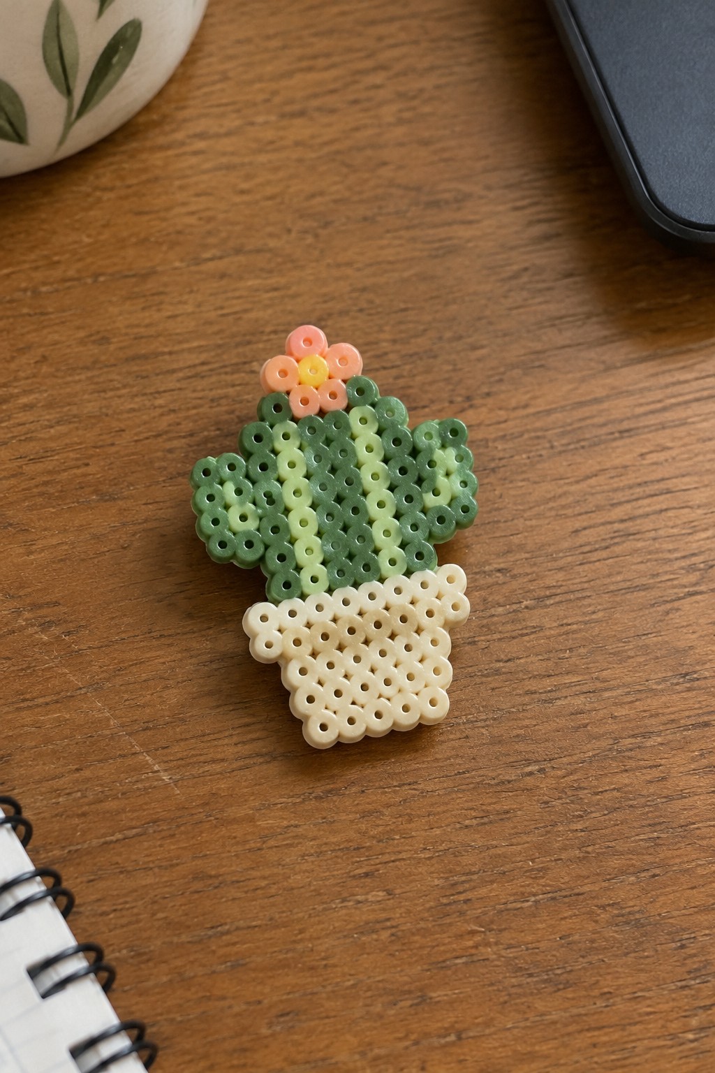 Perler bead potted plant with pink flower on wooden surface