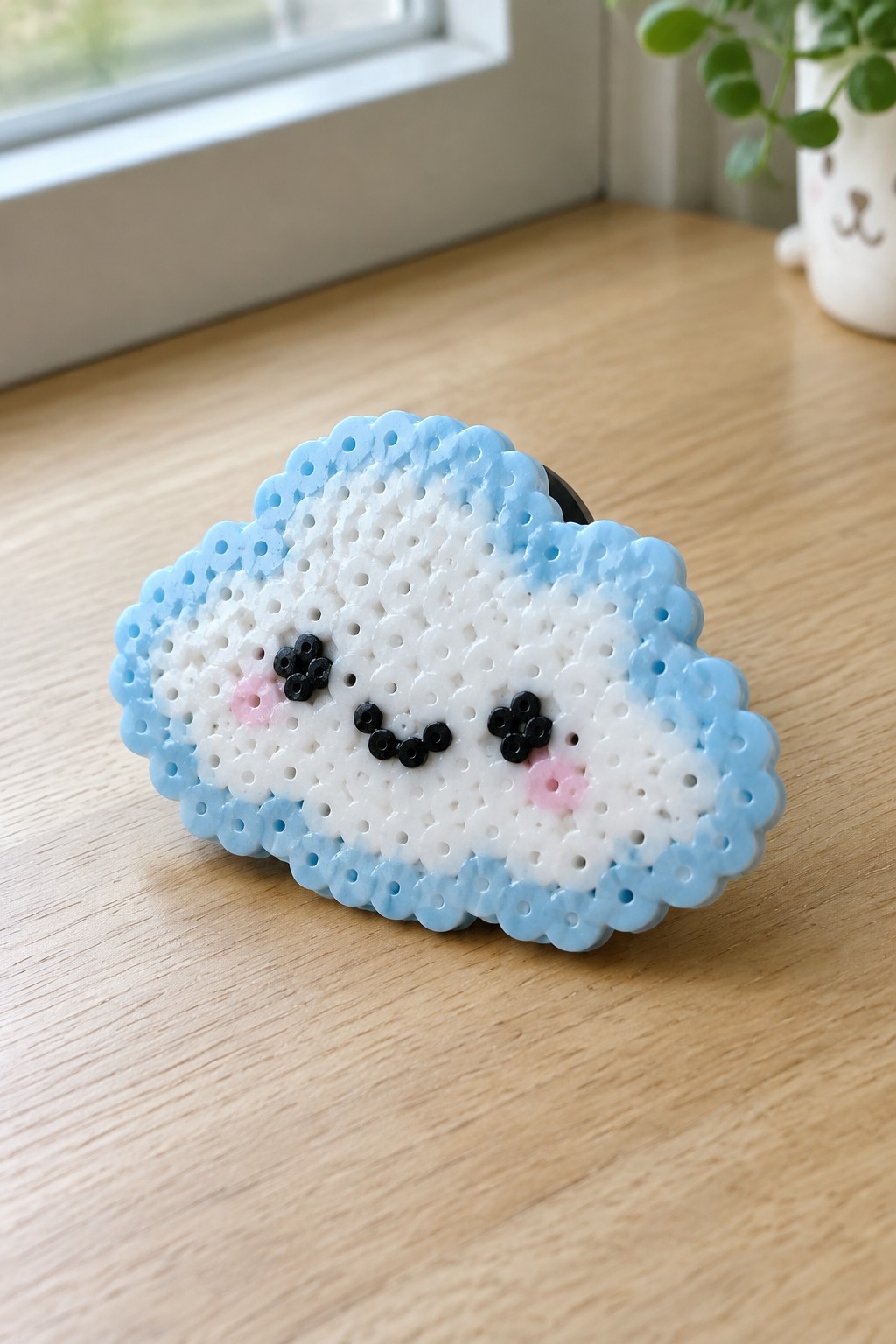 Blue and white perler bead cloud with cute smiling face on wooden table