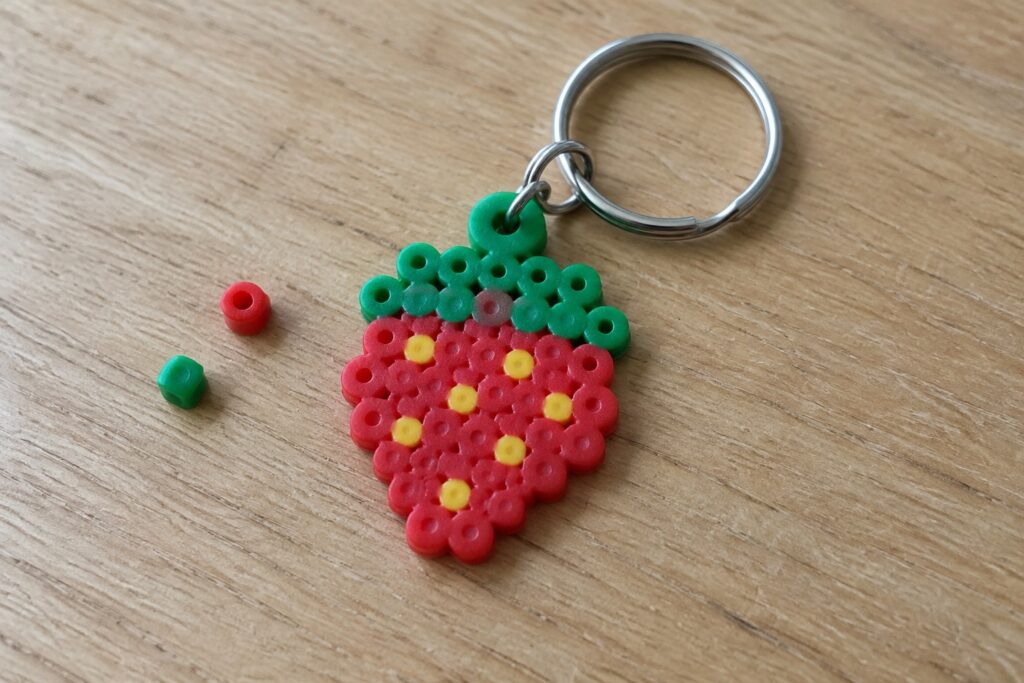 Strawberry Perler bead keychain with red body, yellow seeds, green leaves, metal ring