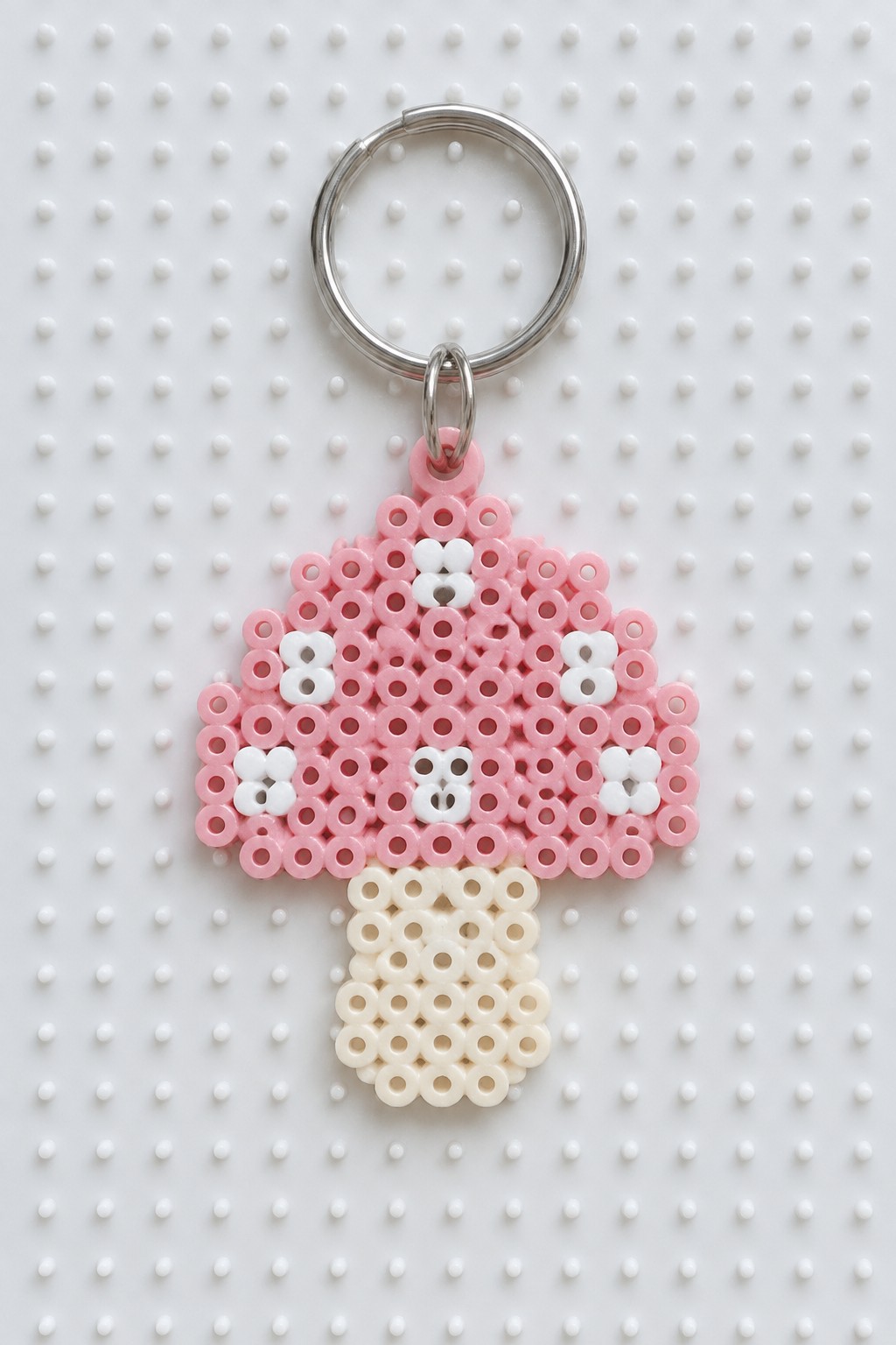 Pink perler bead mushroom keychain with white spots and silver ring