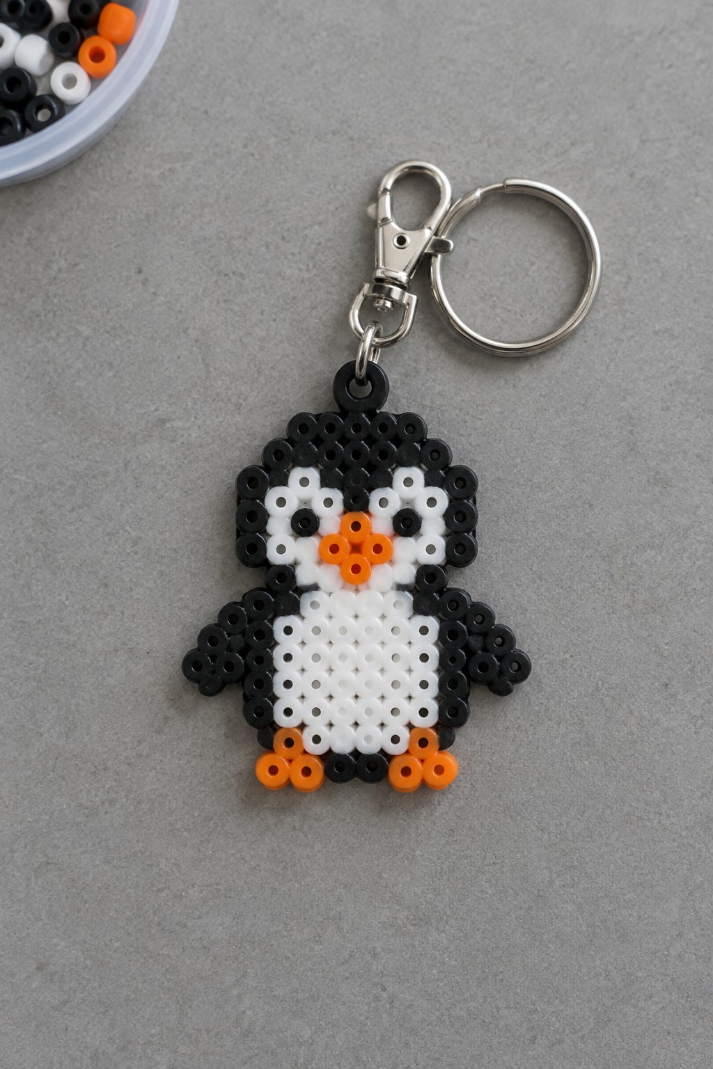 Perler bead penguin keychain in black, white, and orange with metal ring