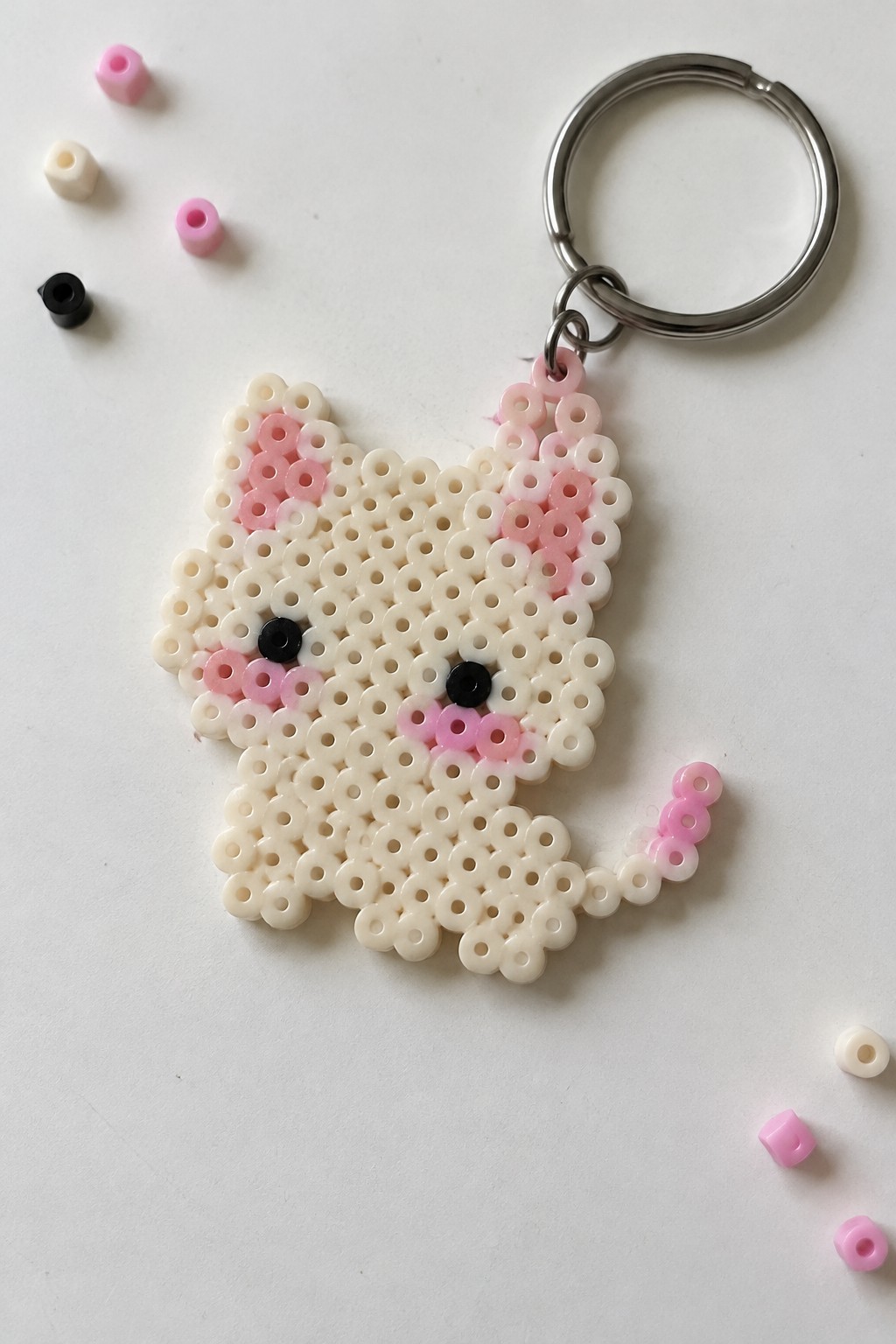 Perler bead white cat keychain with pink ears, cheeks, tail and metal ring