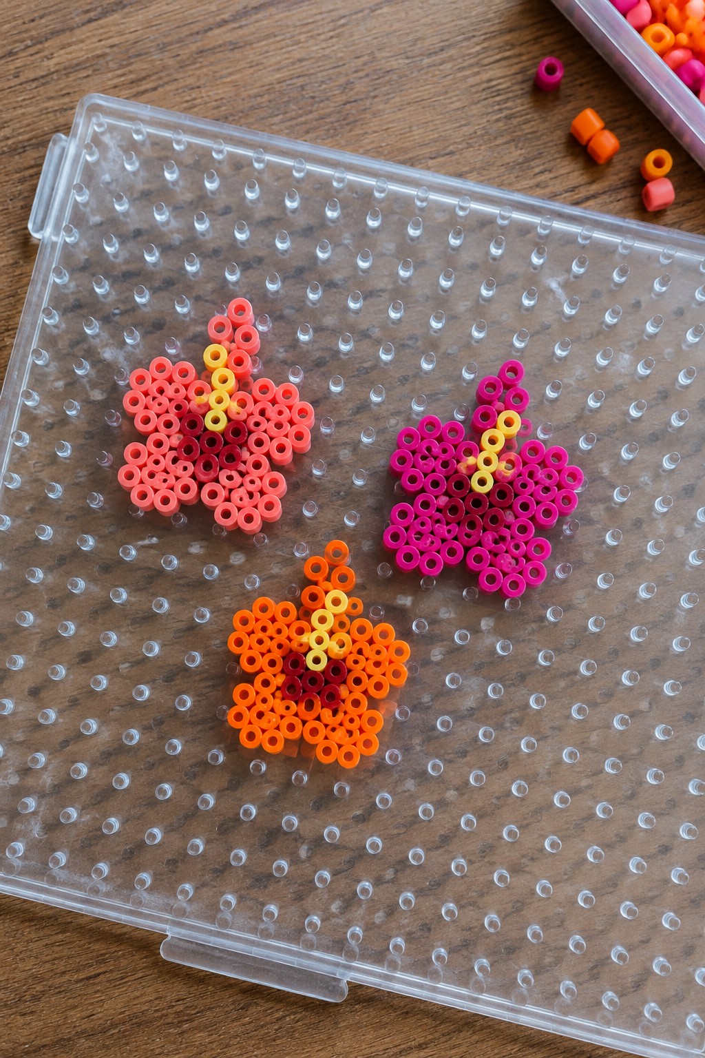 Three gradient bead apples in red, orange, pink on clear pegboard