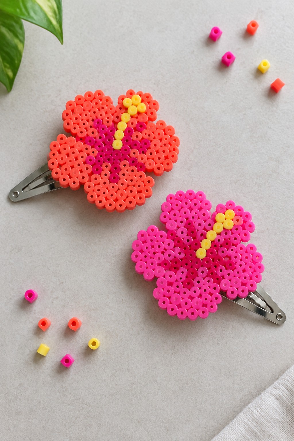 Two perler bead heart hair clips in bright pink and orange with yellow accents