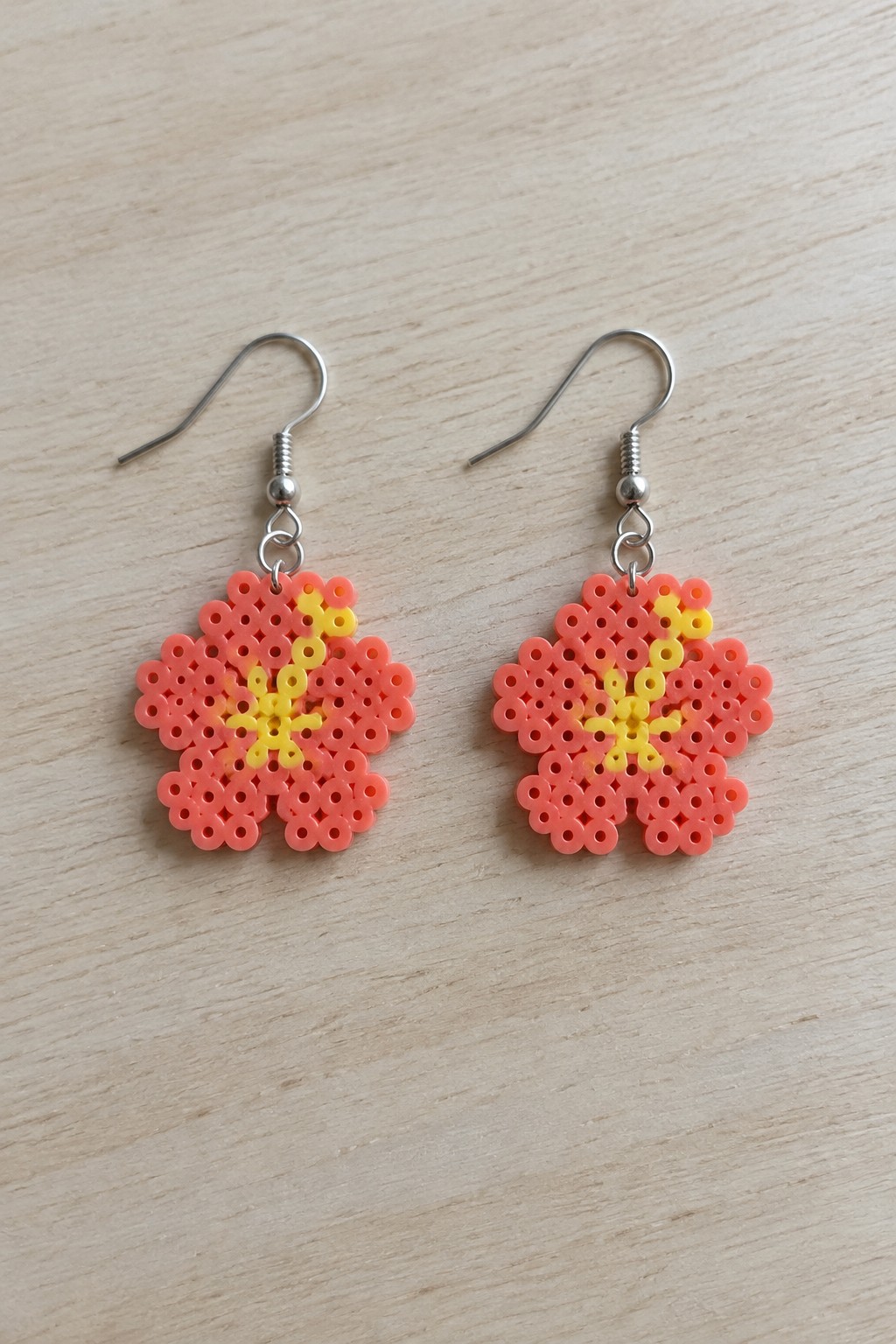 Pink and yellow flower perler bead earrings with silver hooks on wood