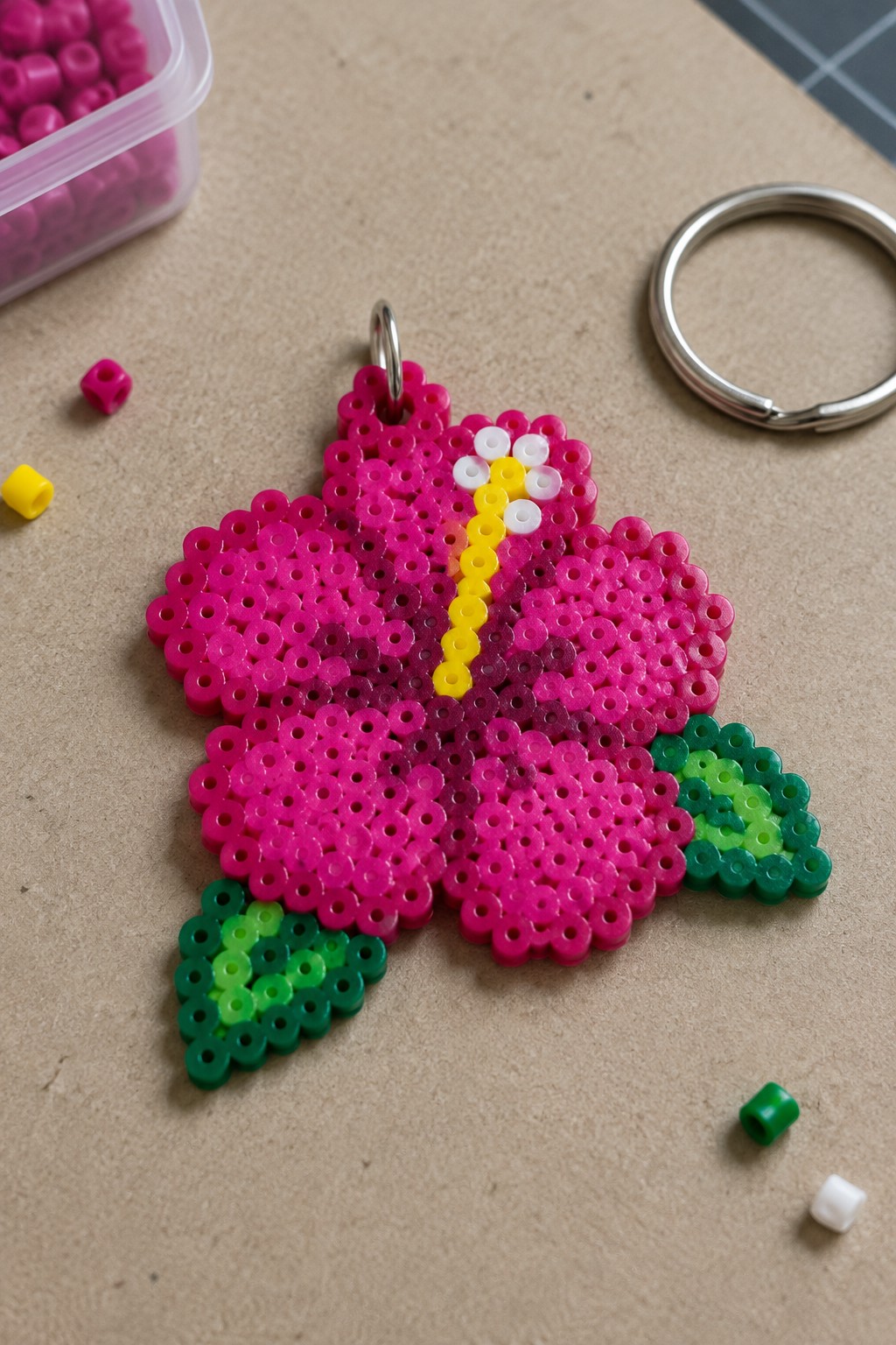 Pink perler bead butterfly keychain with yellow center and green leaf accents