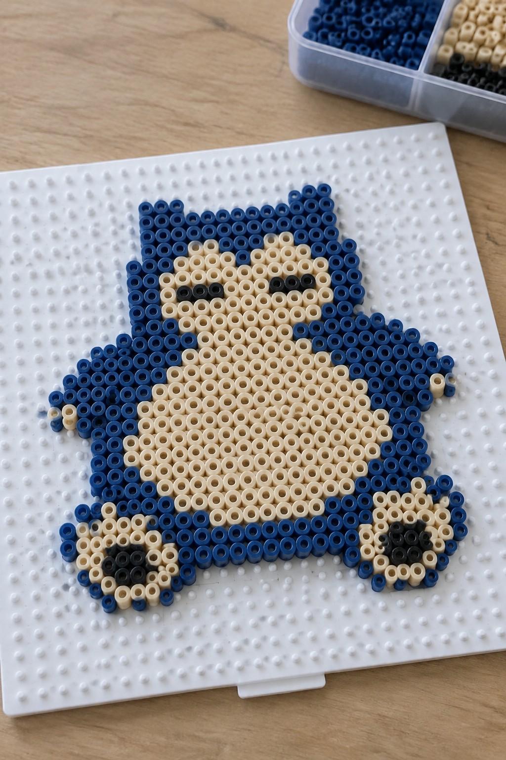 Snorlax Perler bead figure in blue beige and black on white pegboard