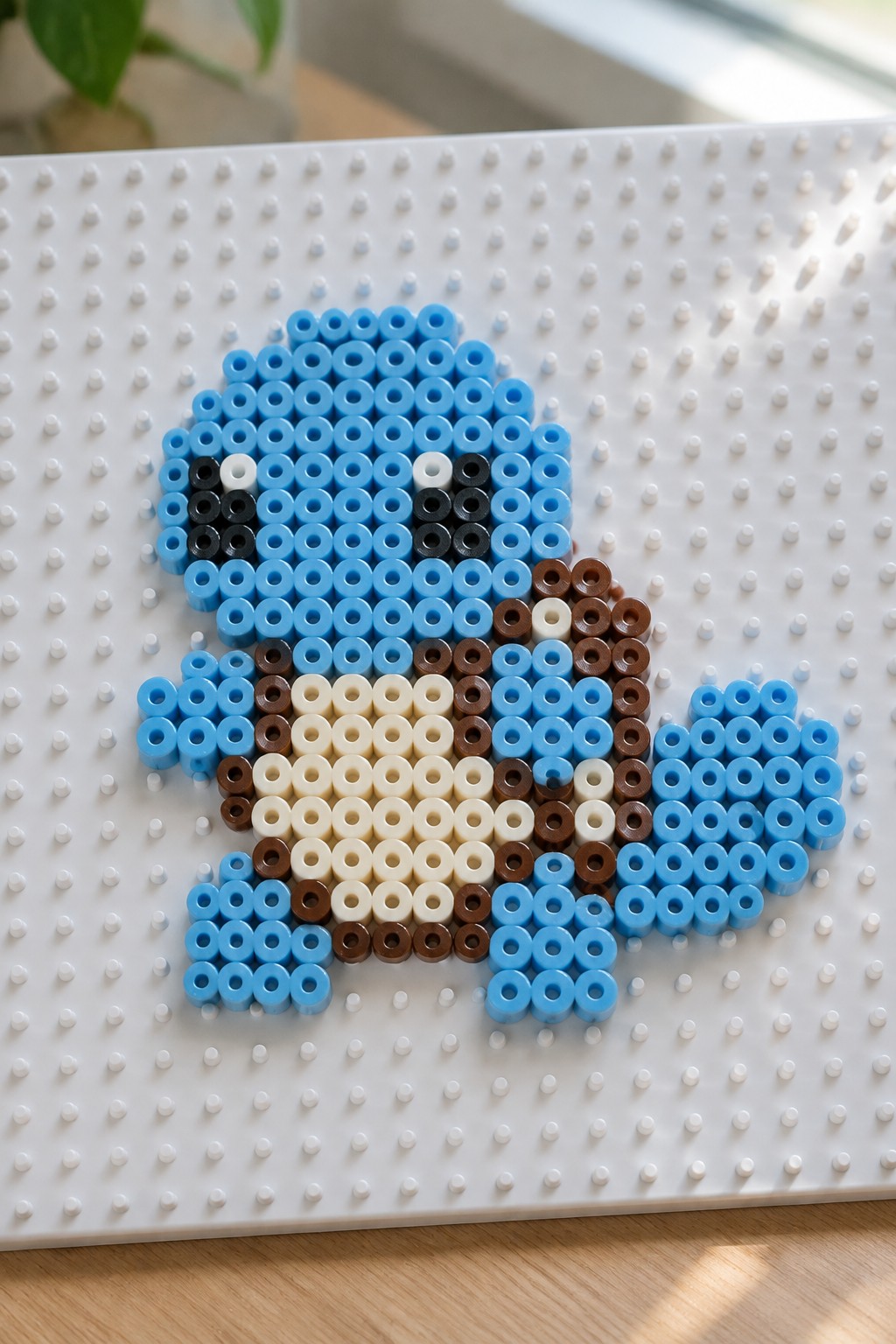 Blue perler bead figure with brown accents on white pegboard.