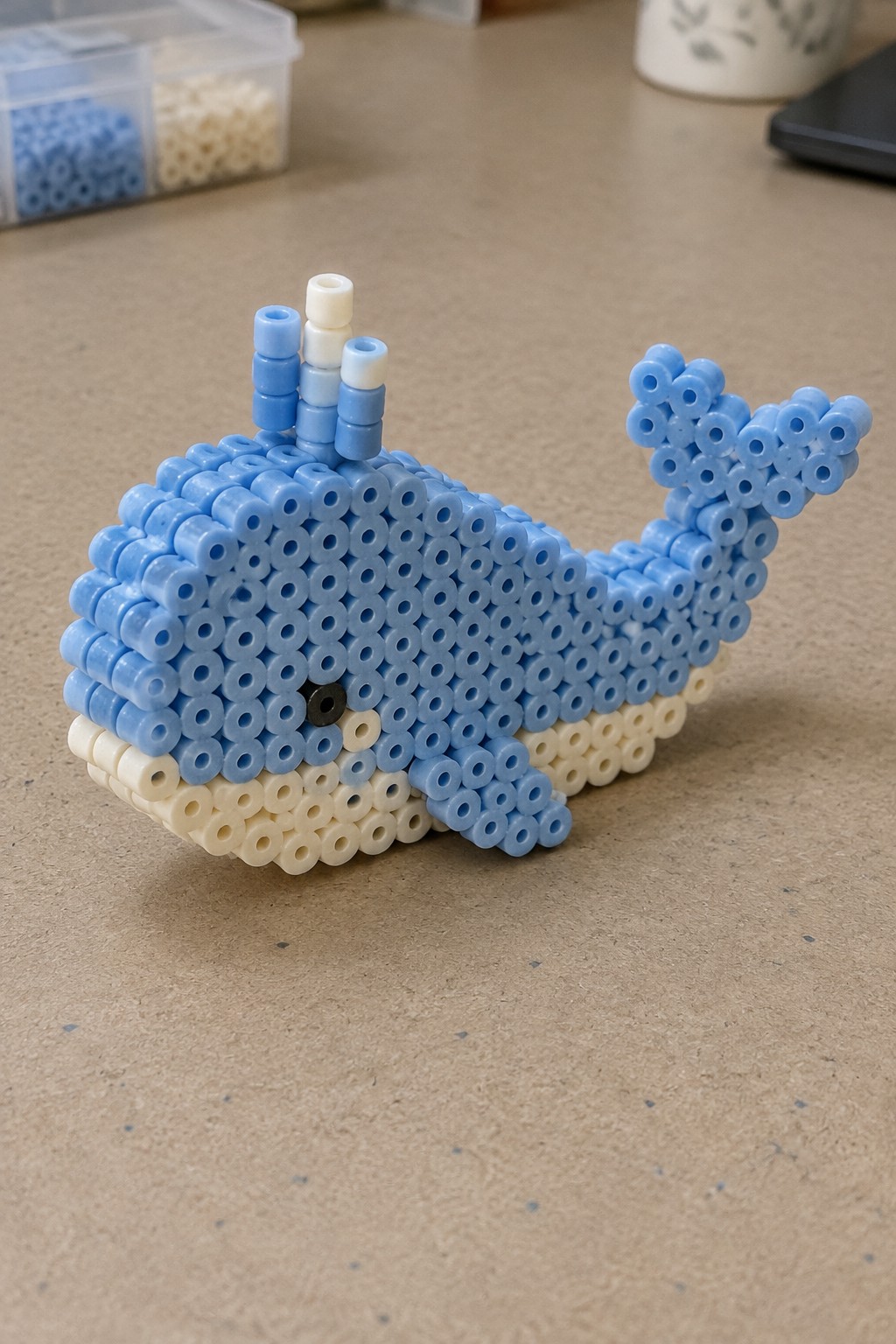 Blue perler bead whale with white belly, tail, and stacked spout