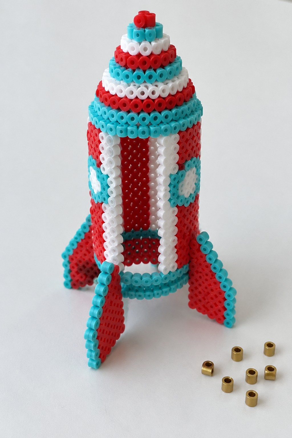 Striped red white and cyan perler bead rocket with fins and gold beads