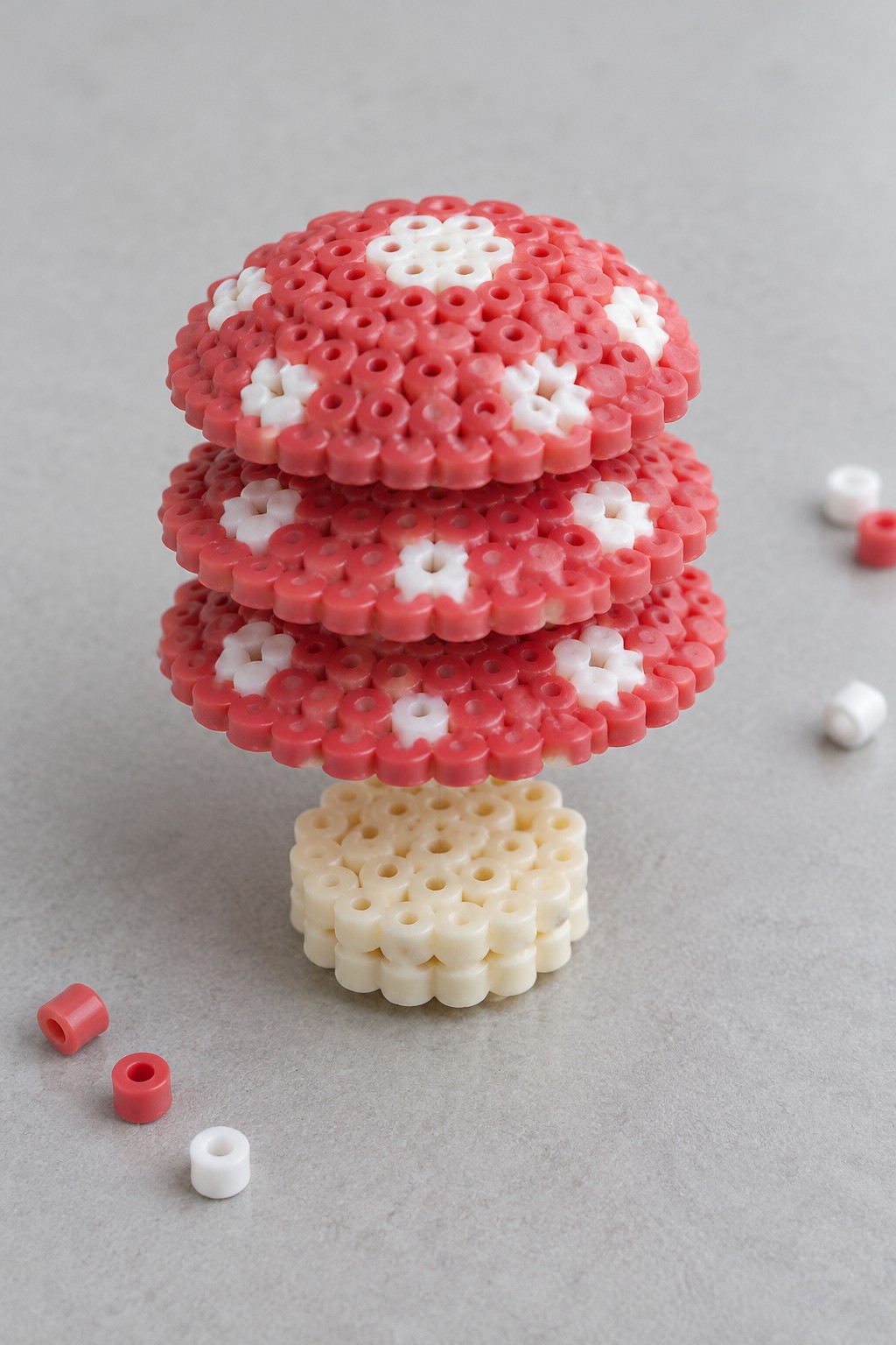 Red and white Perler bead mushroom with beige stem and scattered loose beads