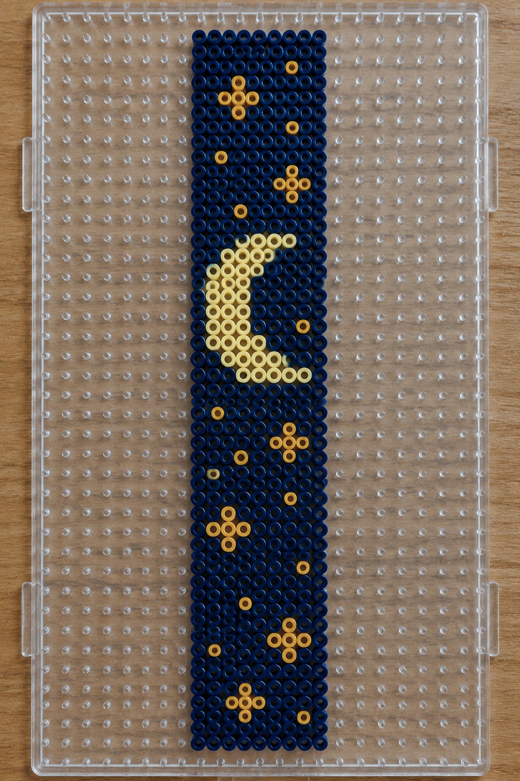 Vertical Perler bead bookmark on a pegboard with dark blue beads and a yellow lightning bolt design.
