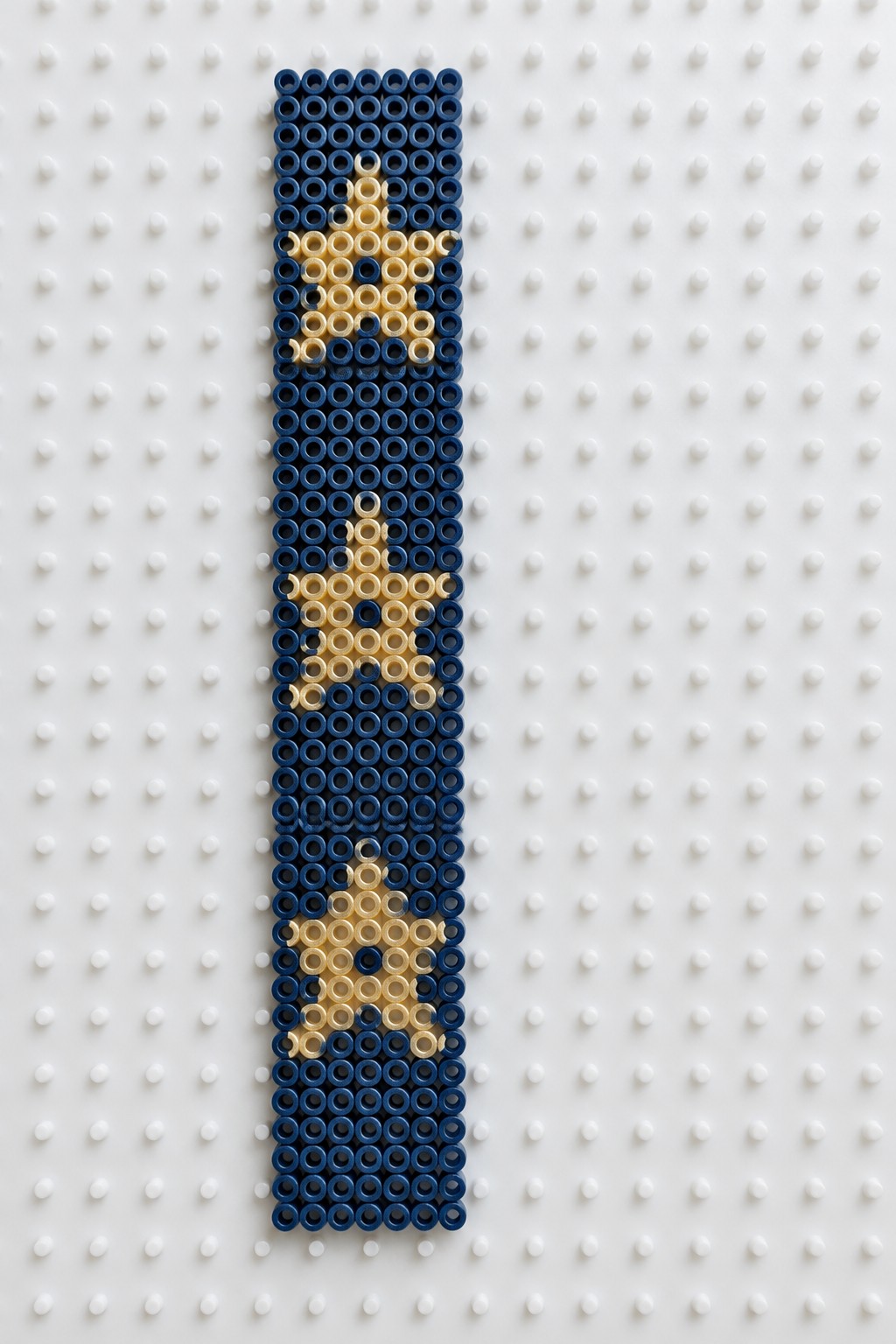 Blue and yellow beaded panel with three yellow stars on white pegboard