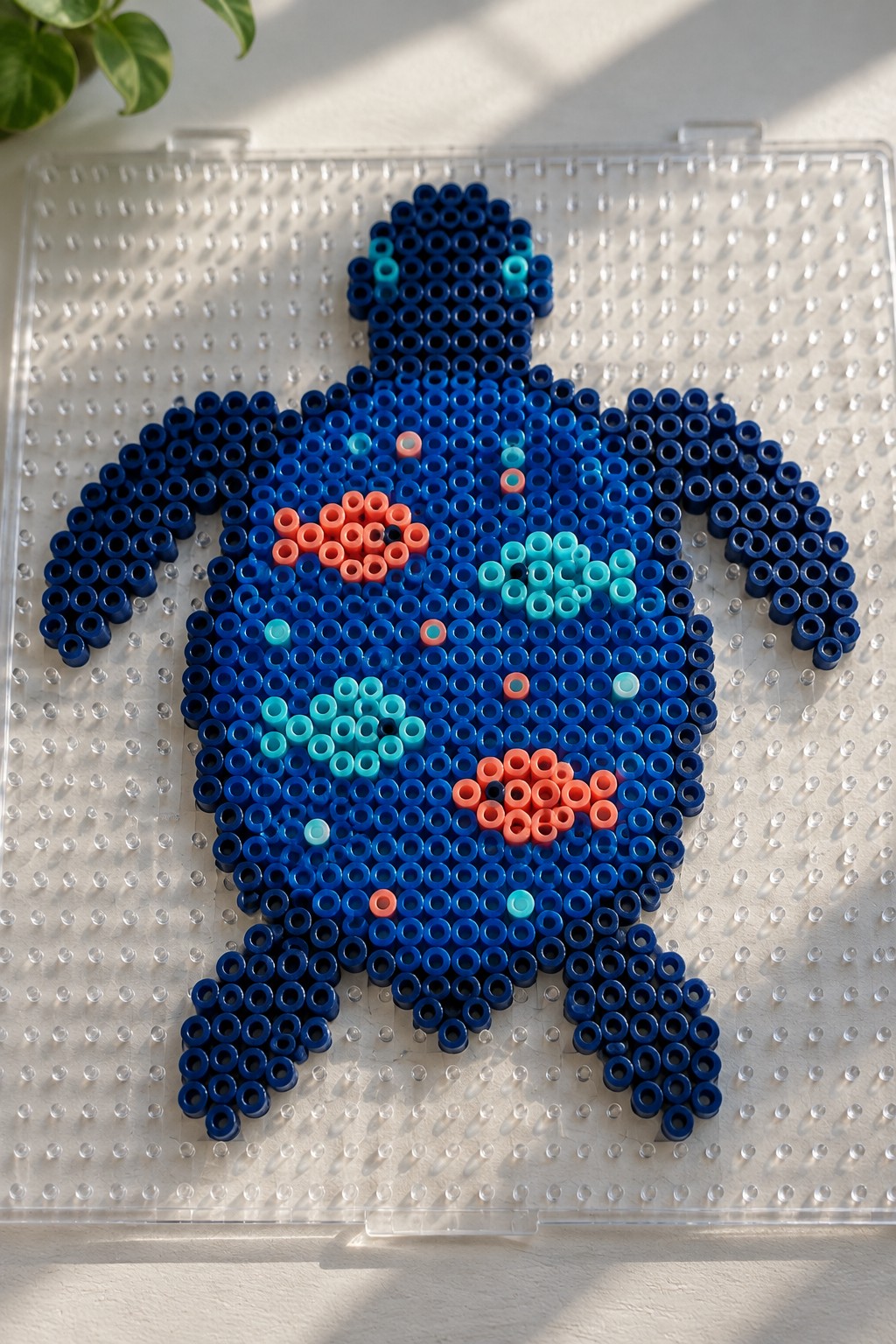 Blue perler bead sea turtle with orange and cyan shell details on pegboard