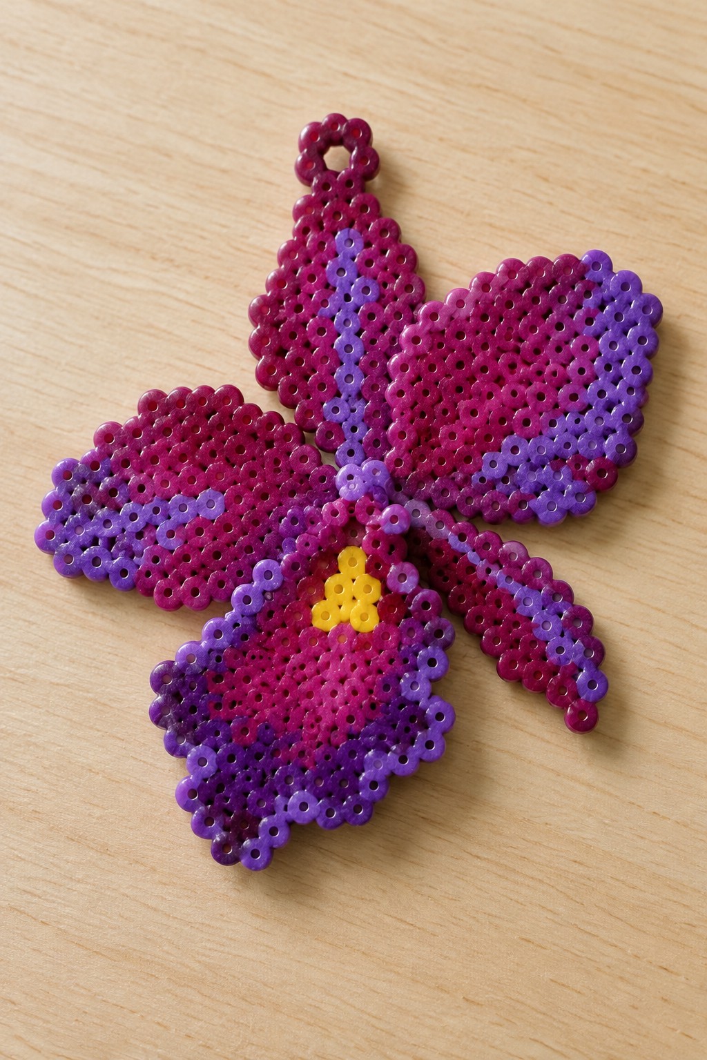 Perler bead flower with purple-pink gradient petals, yellow center, and hanging loop.