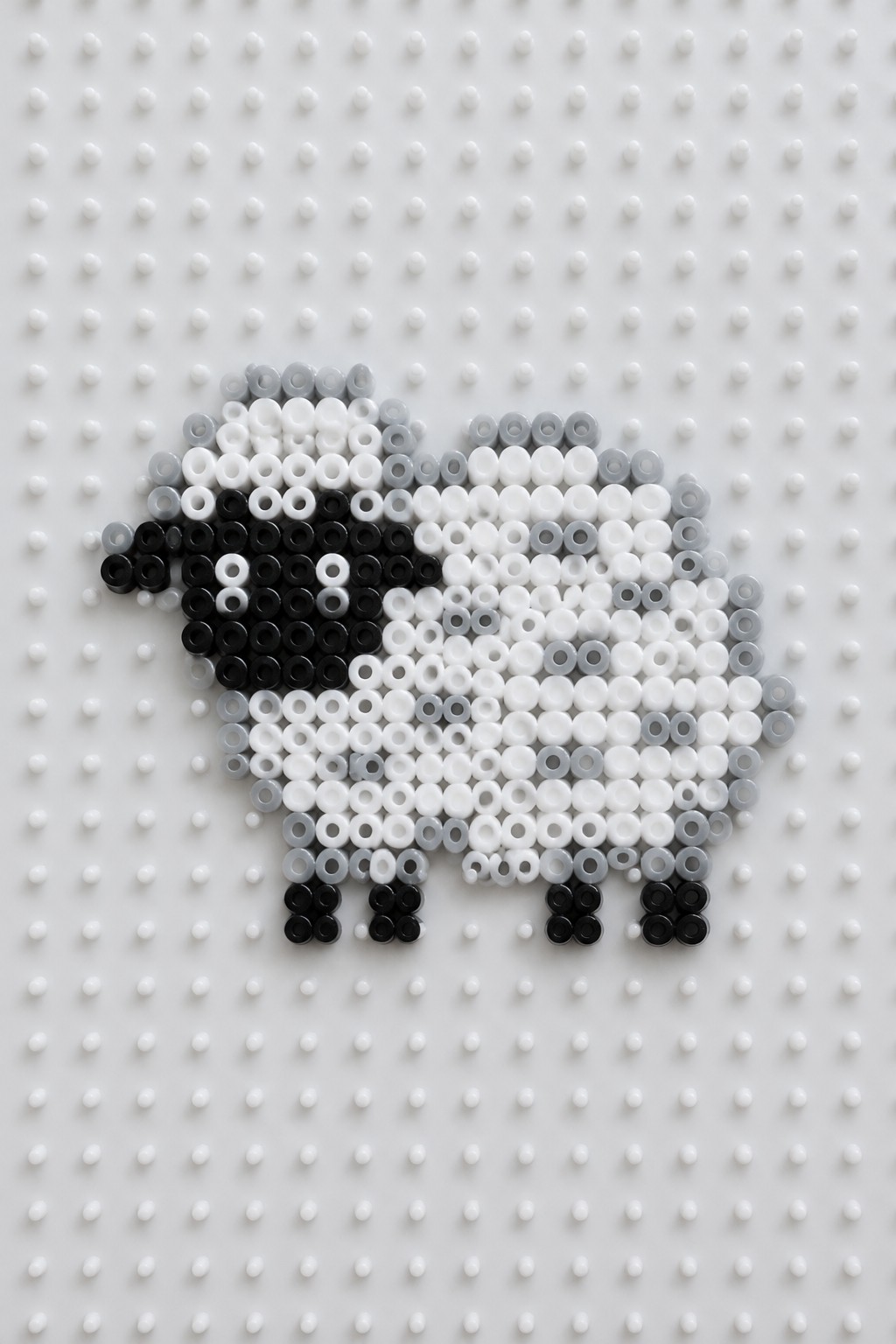 Black and white sheep made of beads on a pegboard.