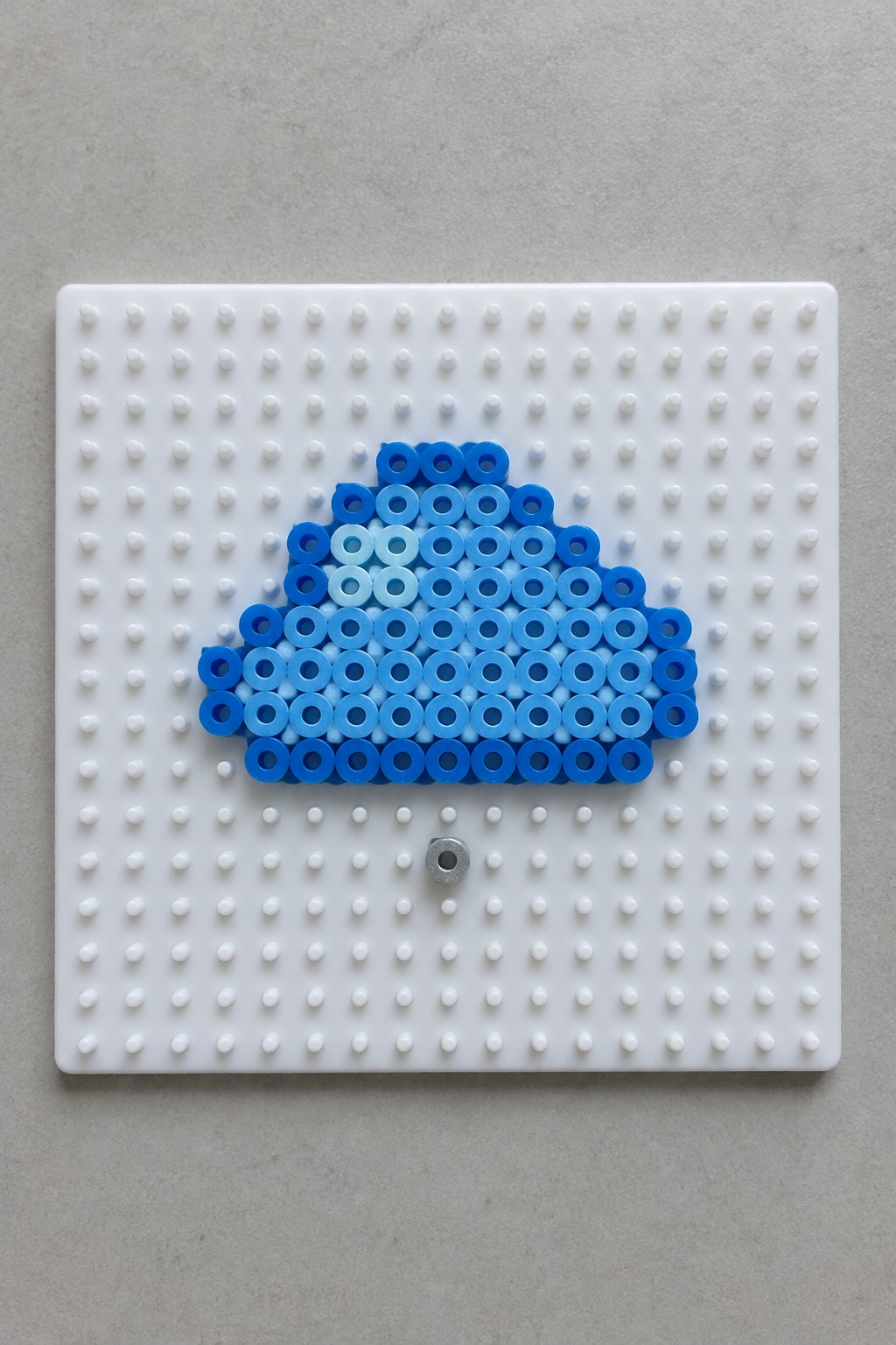 Blue gradient cloud of beads on white pegboard with metal ring below