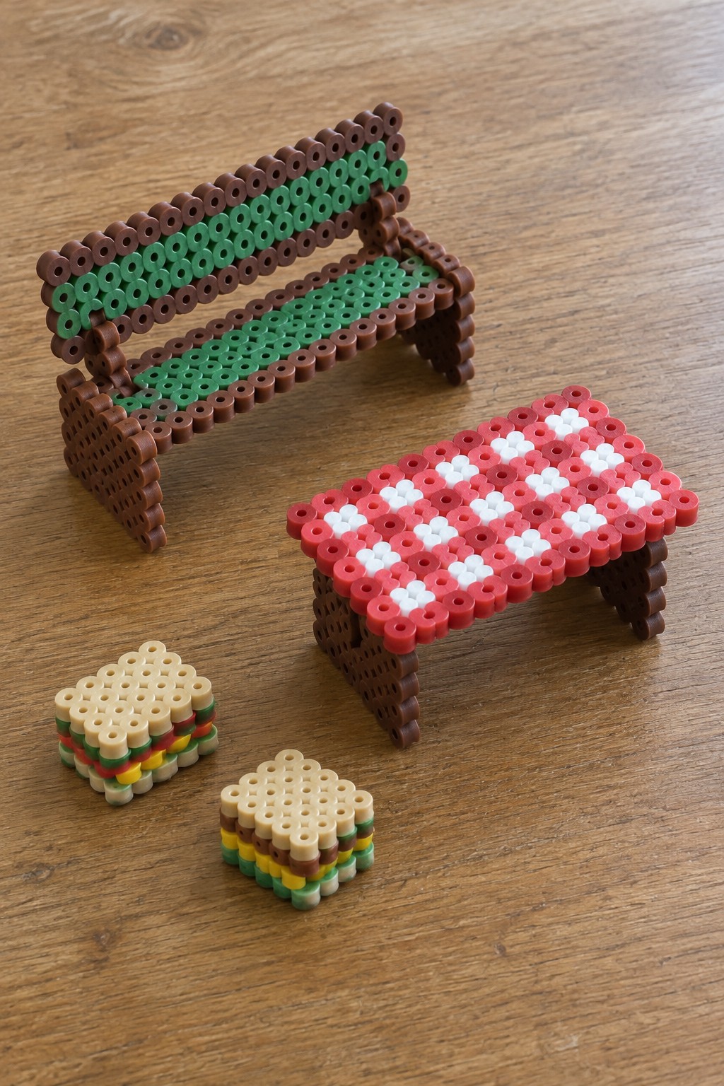 Perler bead bench, striped table, and two small hamburger crafts on wood.