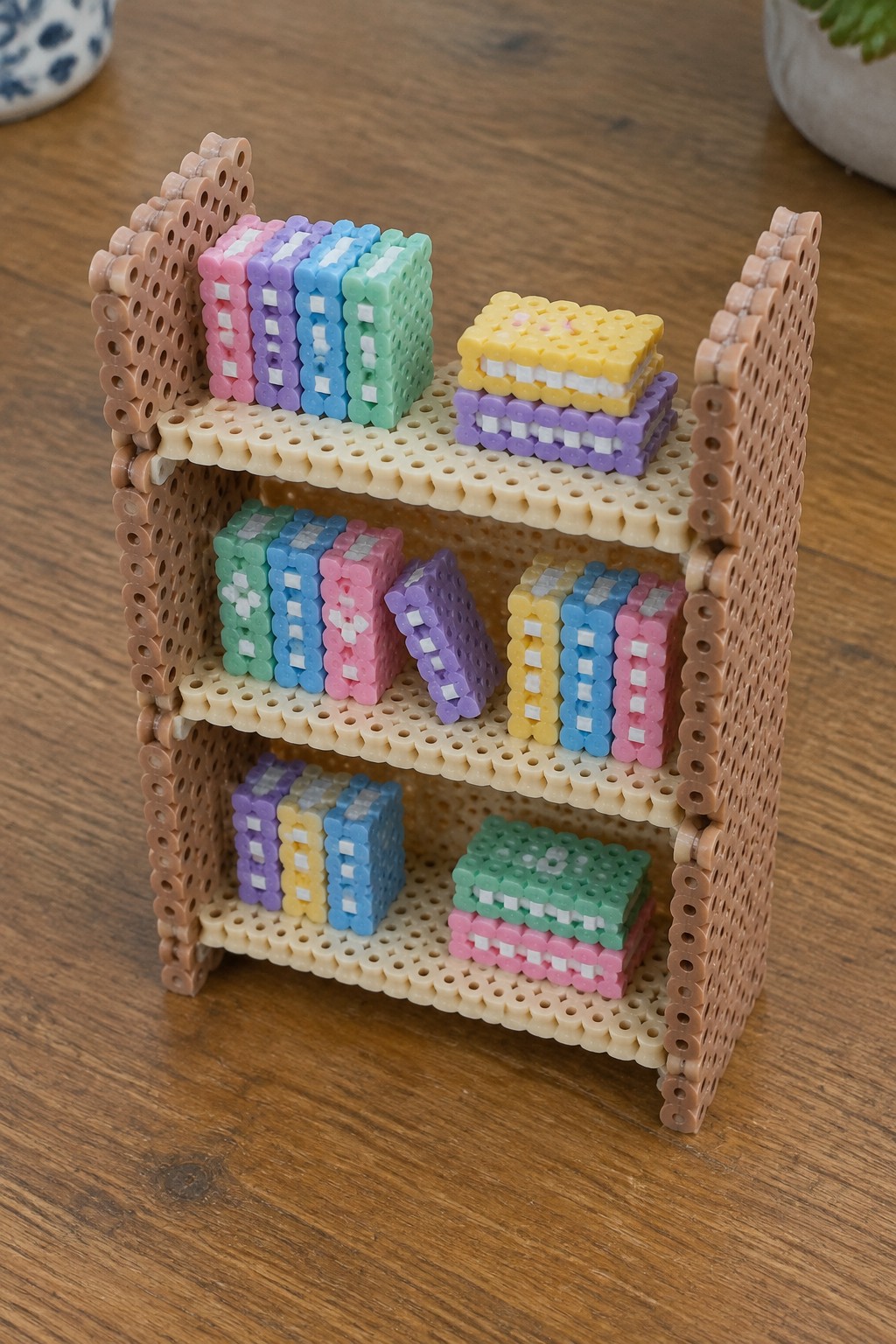 Three-tiered brown bead bookshelf with colorful miniature stacked books on wood.