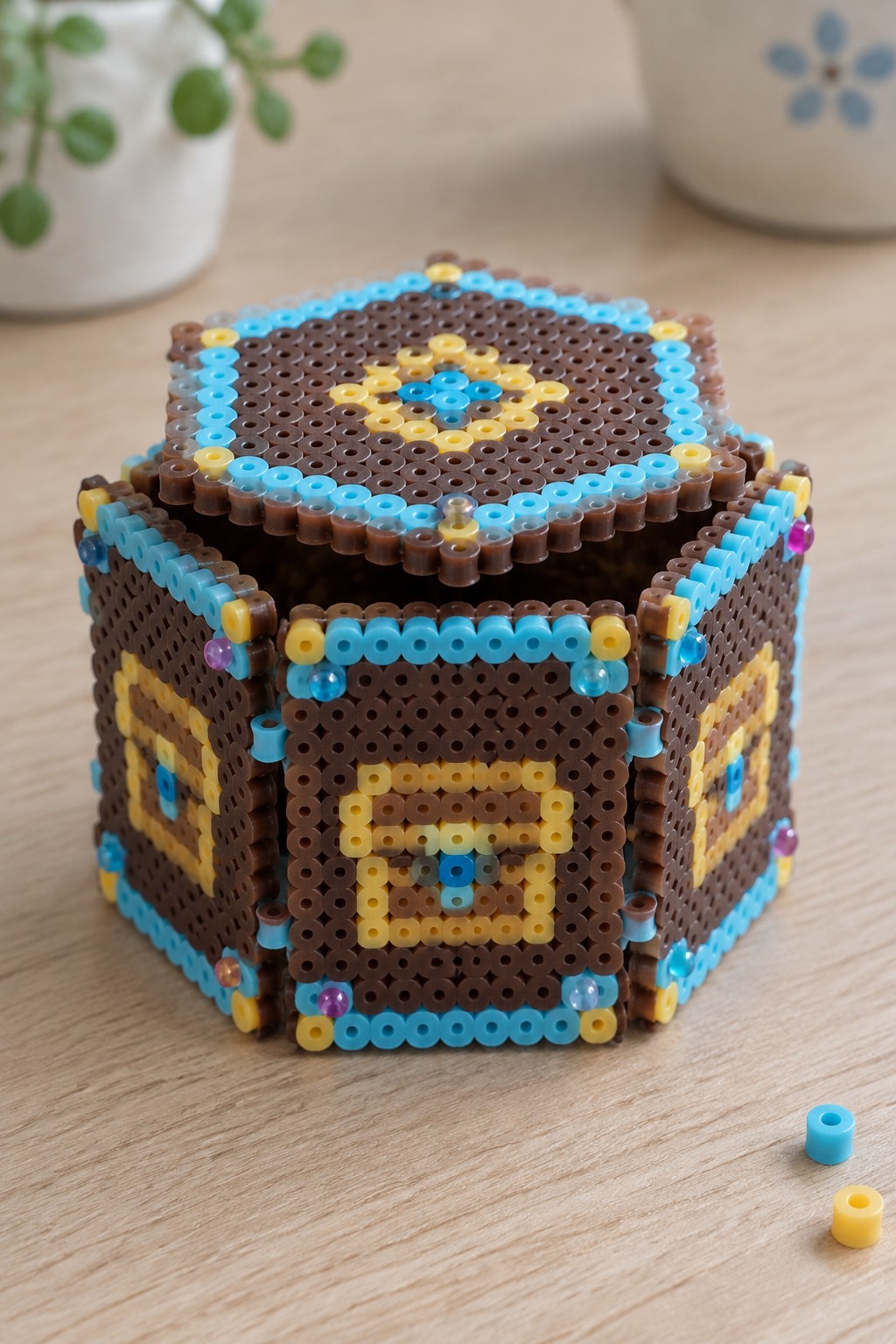 Brown Perler bead box with blue and yellow geometric patterns on wood table
