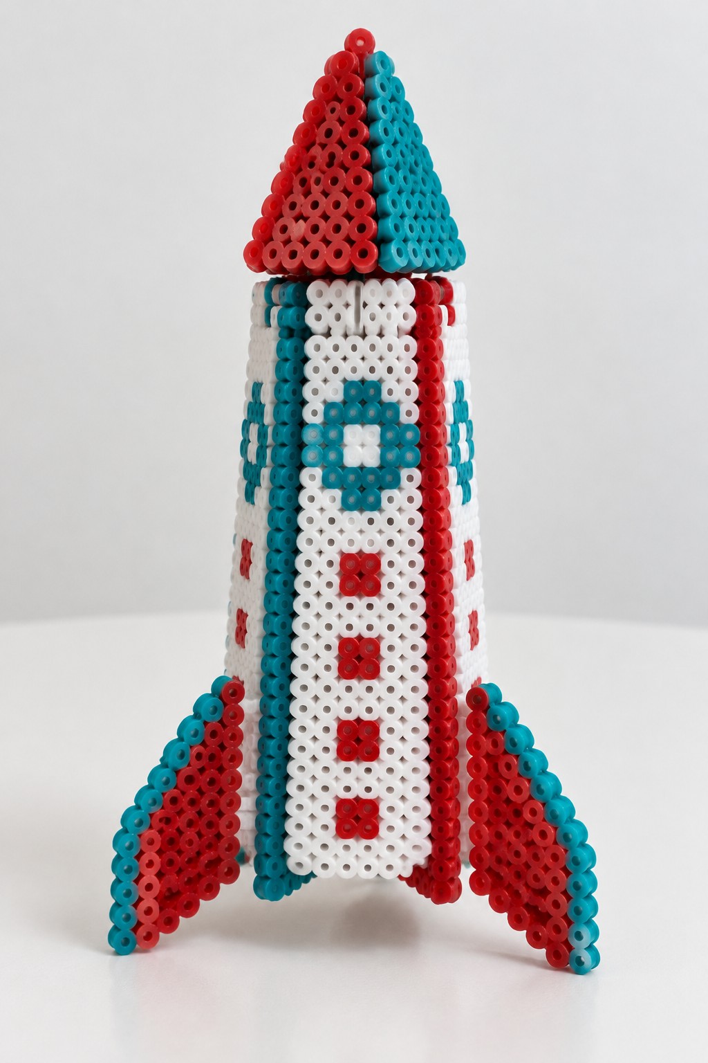 Red white and teal beaded rocket with pointed nose and side fins
